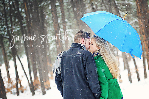 Couple kisses under a blue umbrella at Fox Run Park.