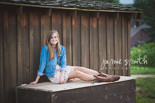 girl sitting on wooden bench by barn