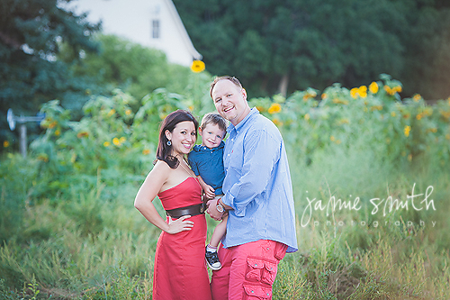 family posing in front of sunflower field