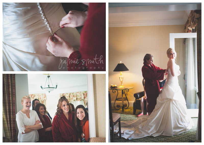 bride getting dress buttoned up while bridesmaids watch in excitement