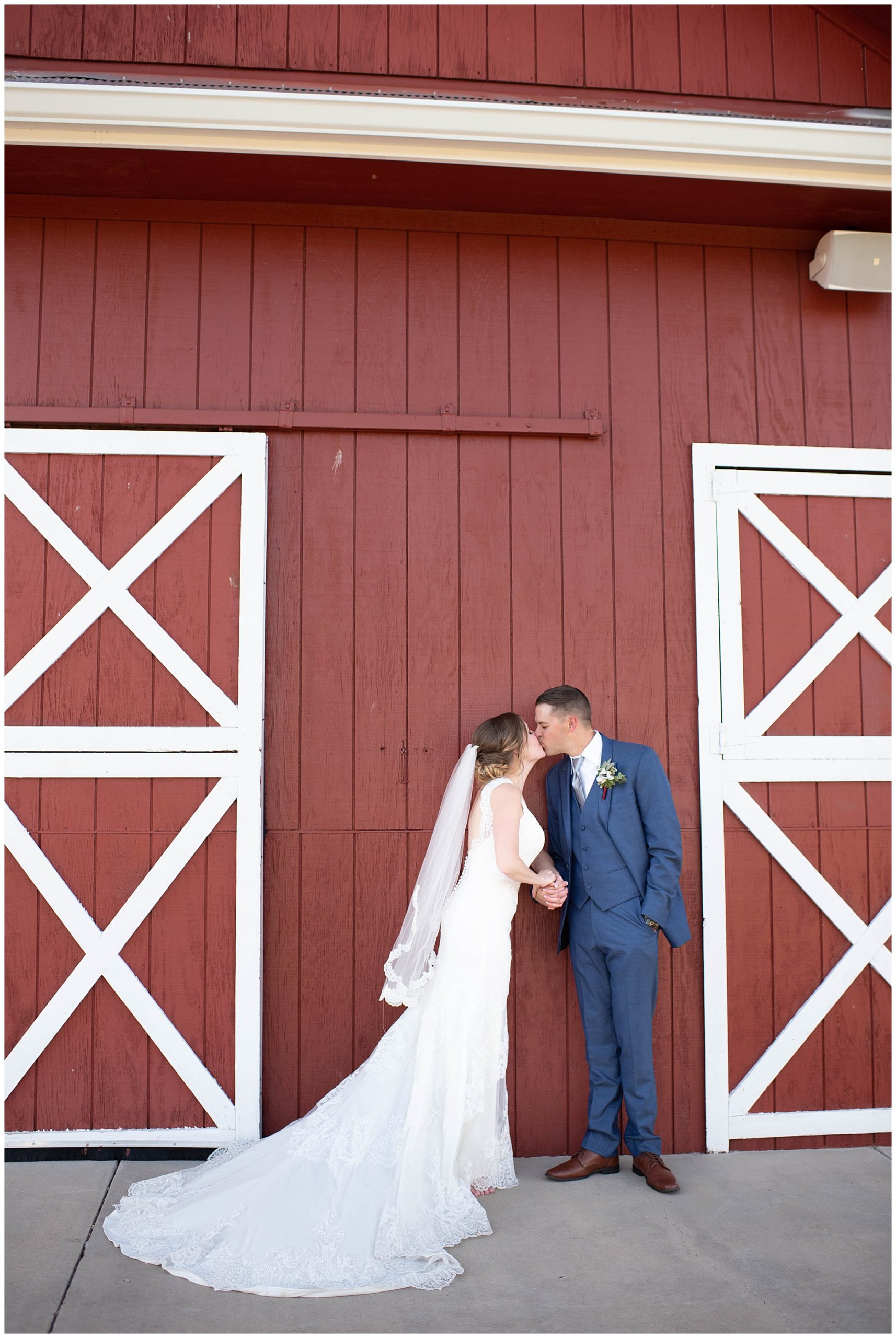 bride and groom sharing a kiss in front of the barn at Crooked Willow Farms Wedding venue