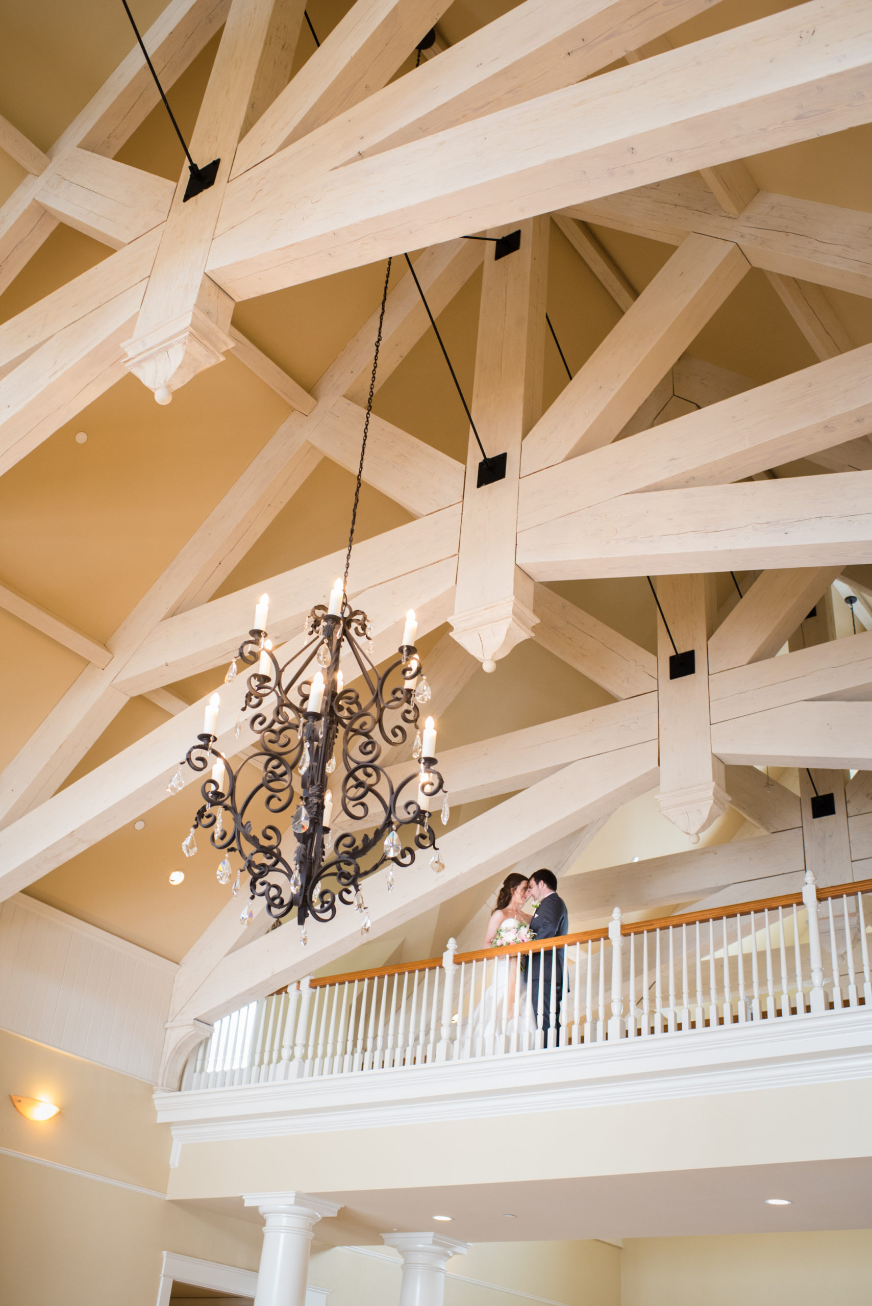 exposed beams and chandelier surrounding the bride and groom at Flying Horse Ranch Wedding venue
