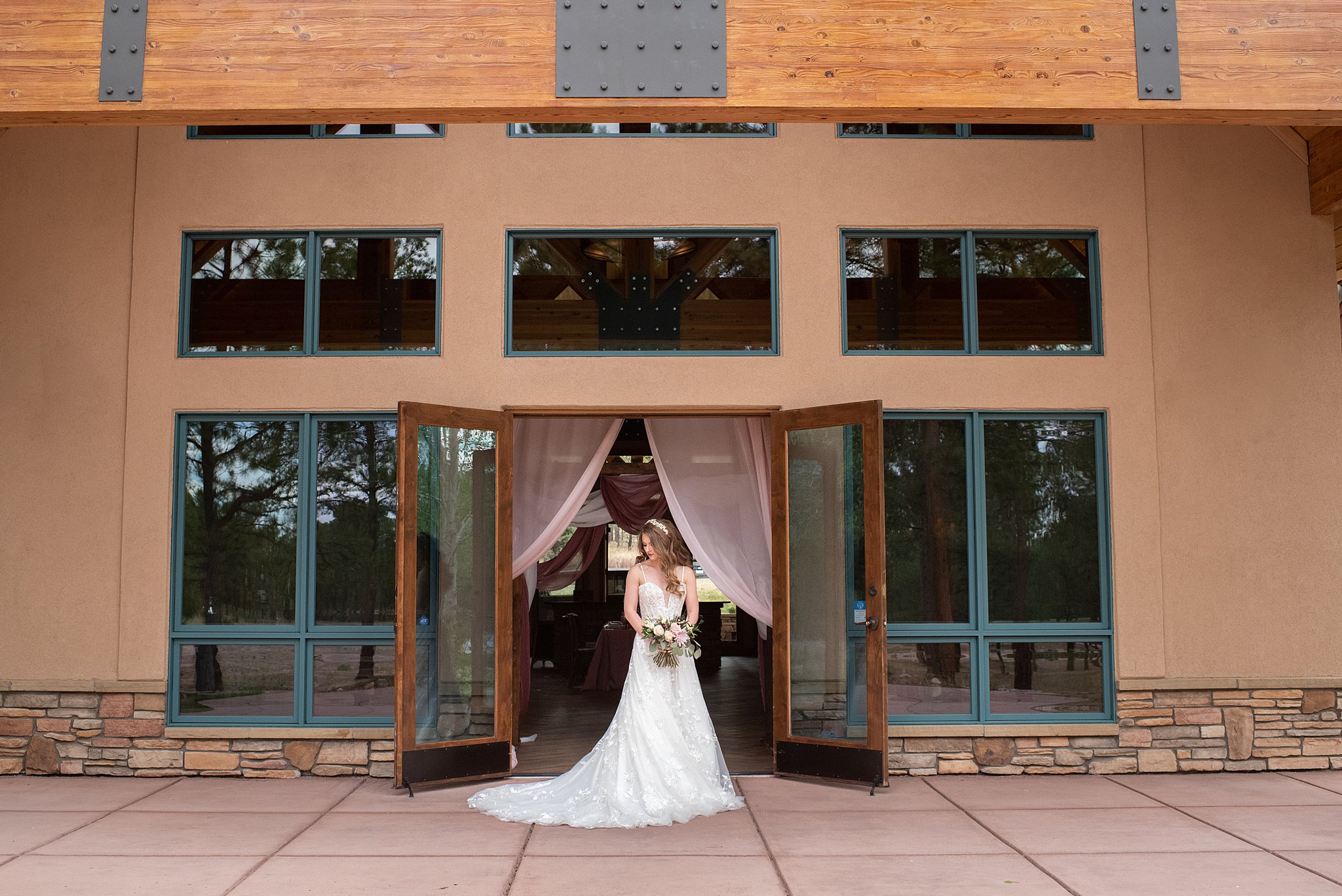 bride holding her flowers stands at the entrance to her reception location