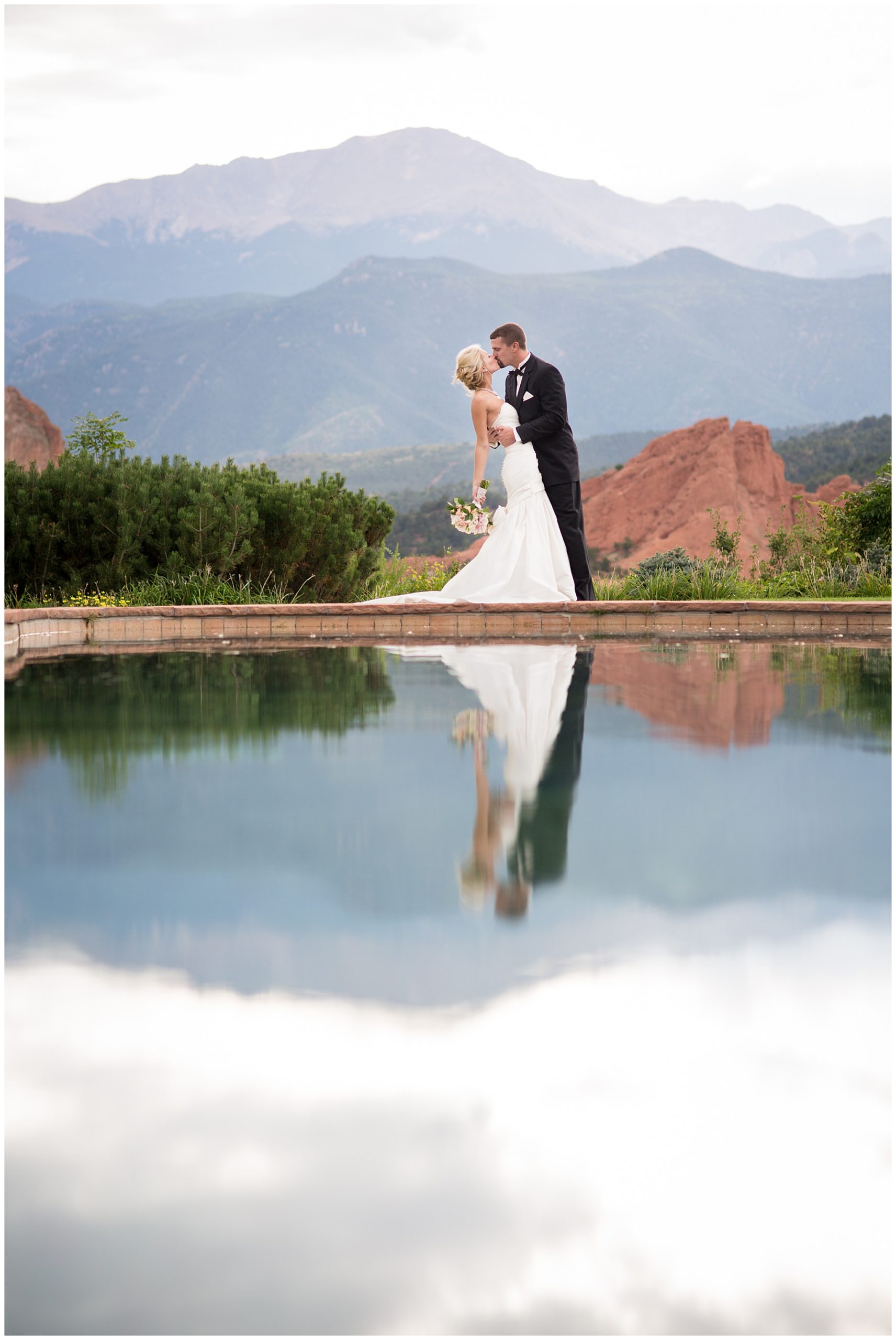 bride and groom standing near the water sharing a kiss at the garden of the gods club wedding venue
