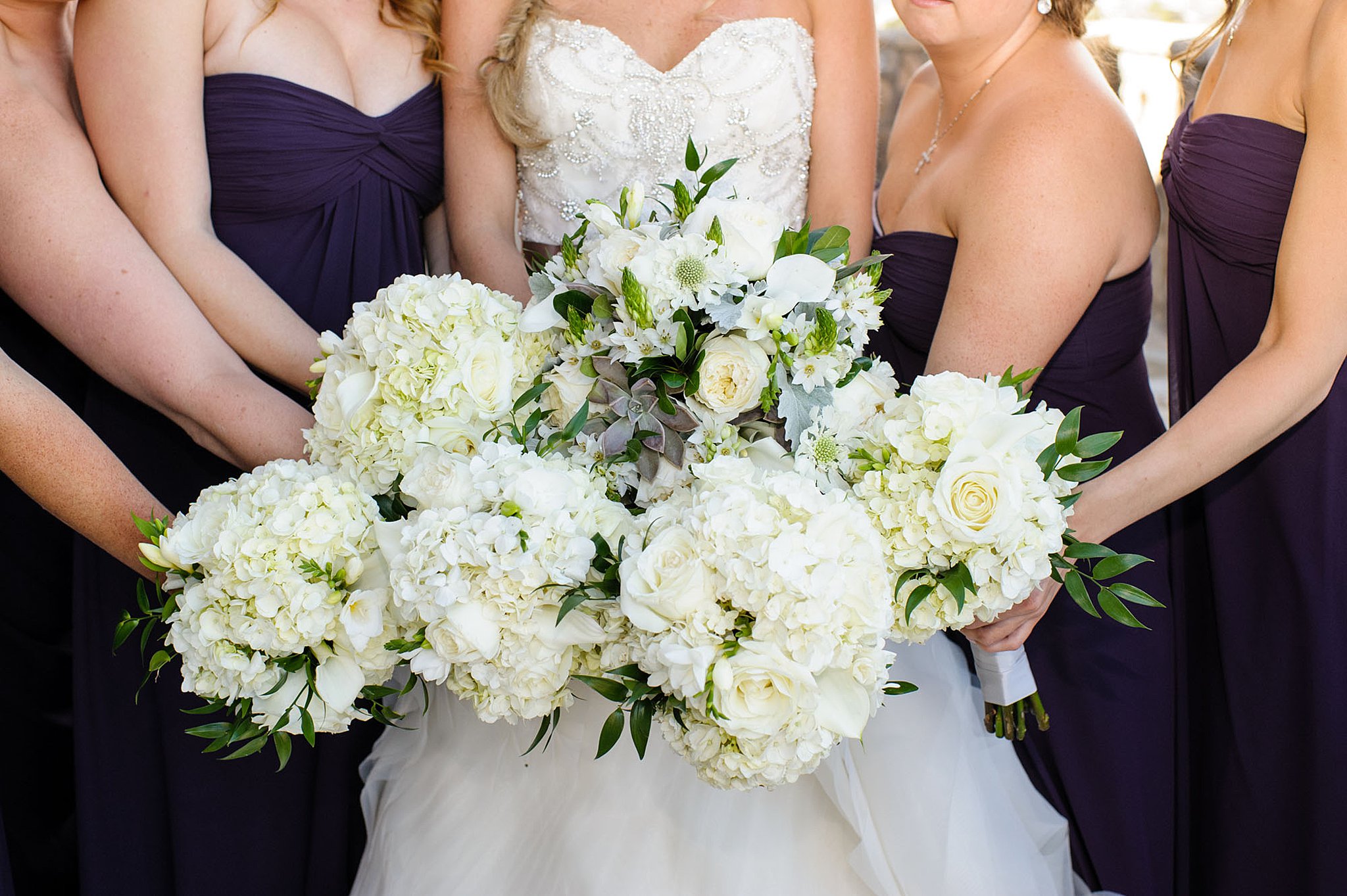 bride and her bridesmaids hold their white bouquets together Colorado springs wedding florists