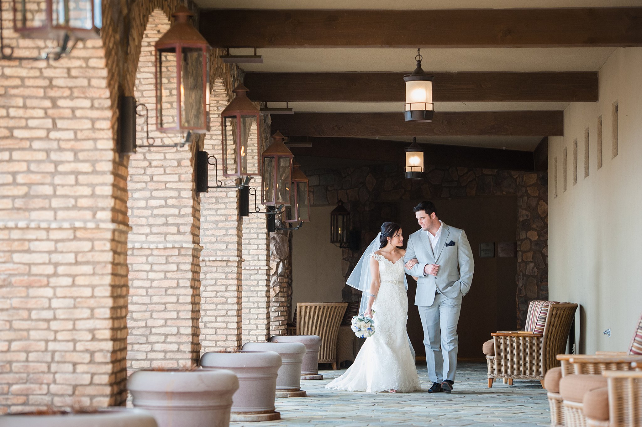 Newlyweds walk down an outdoor hallway on a stone floor arm in arm colorado springs wedding planners