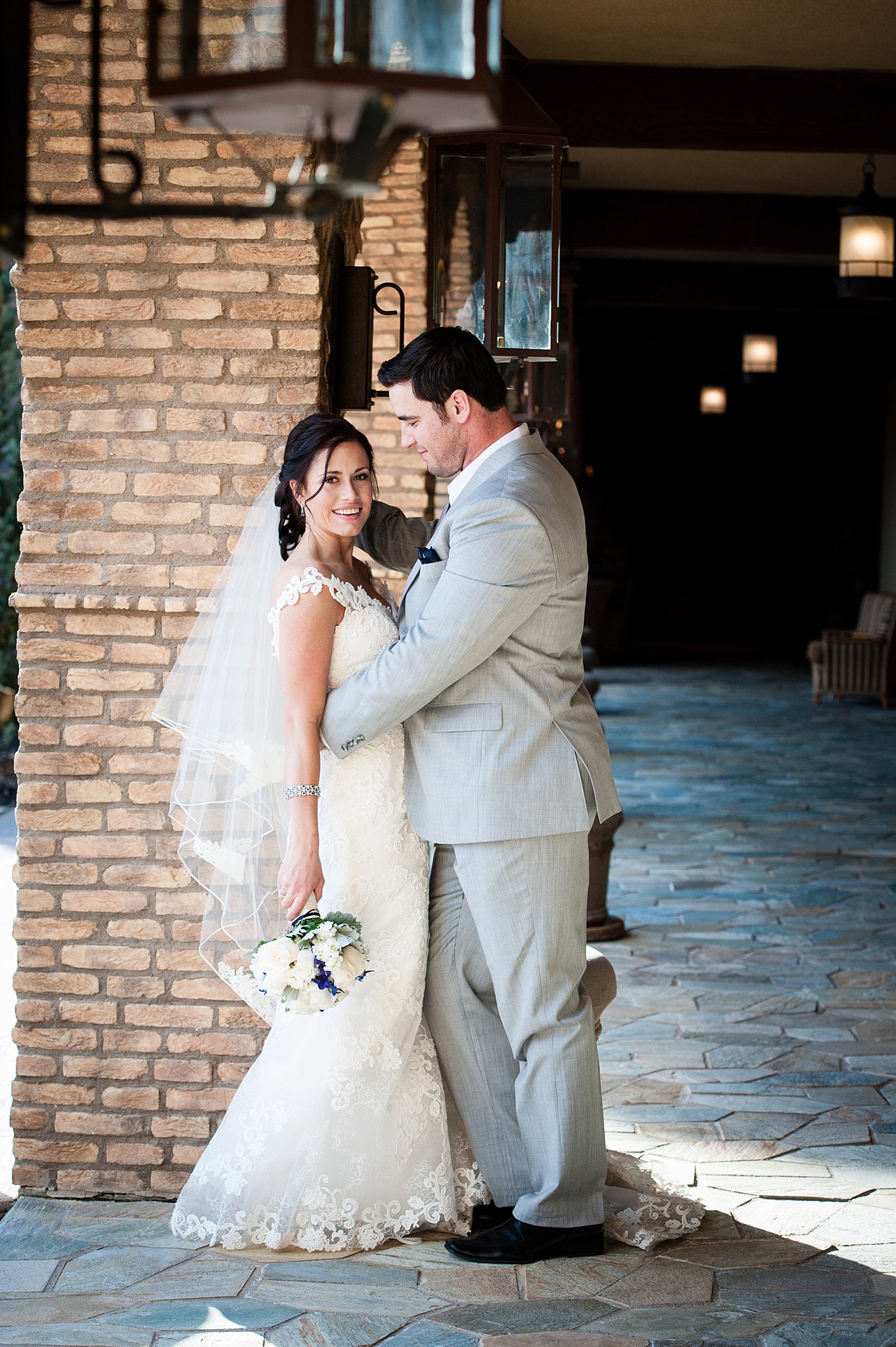 Newlyweds stand holding each other in a stone arch outside colorado springs wedding planners