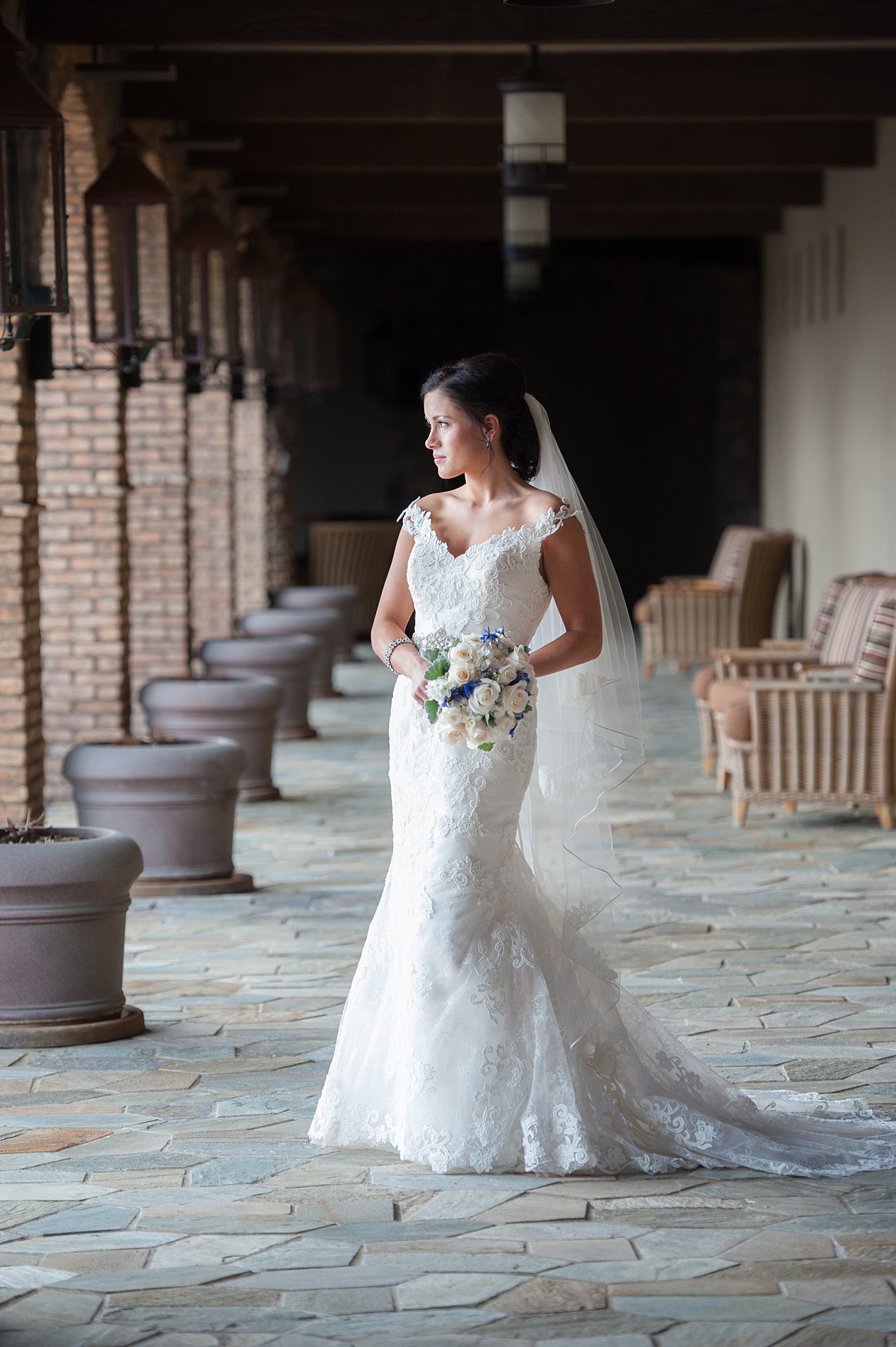Bride in a white dress and long veil stands in on a stone patio colorado springs wedding planners