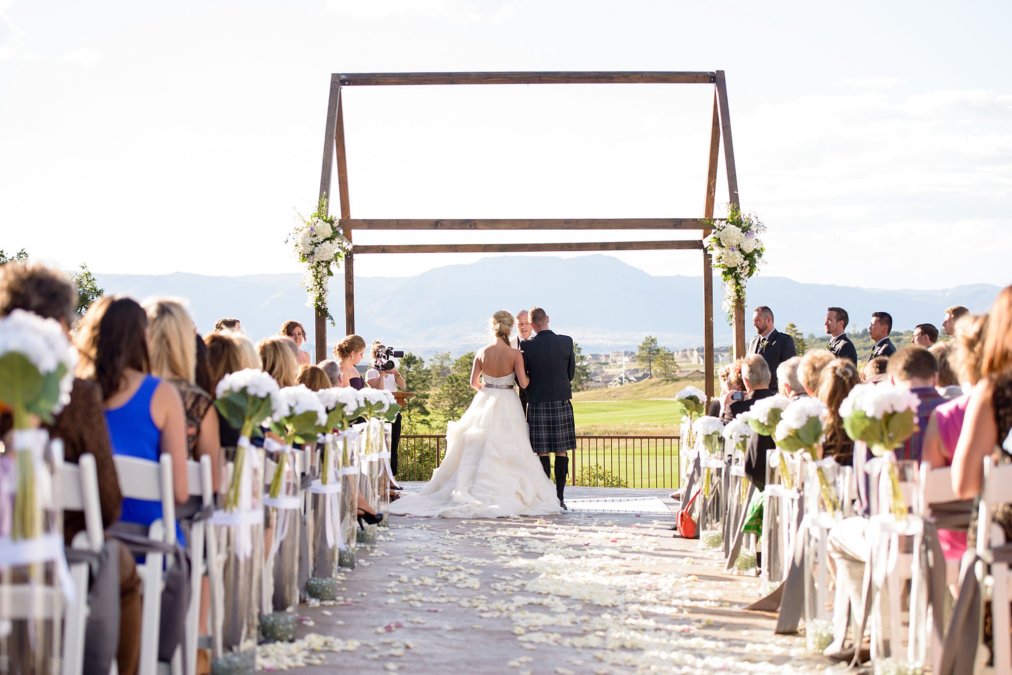 Bride and groom stand under a wooden frame arbor during their ceremony the club at flying horse wedding