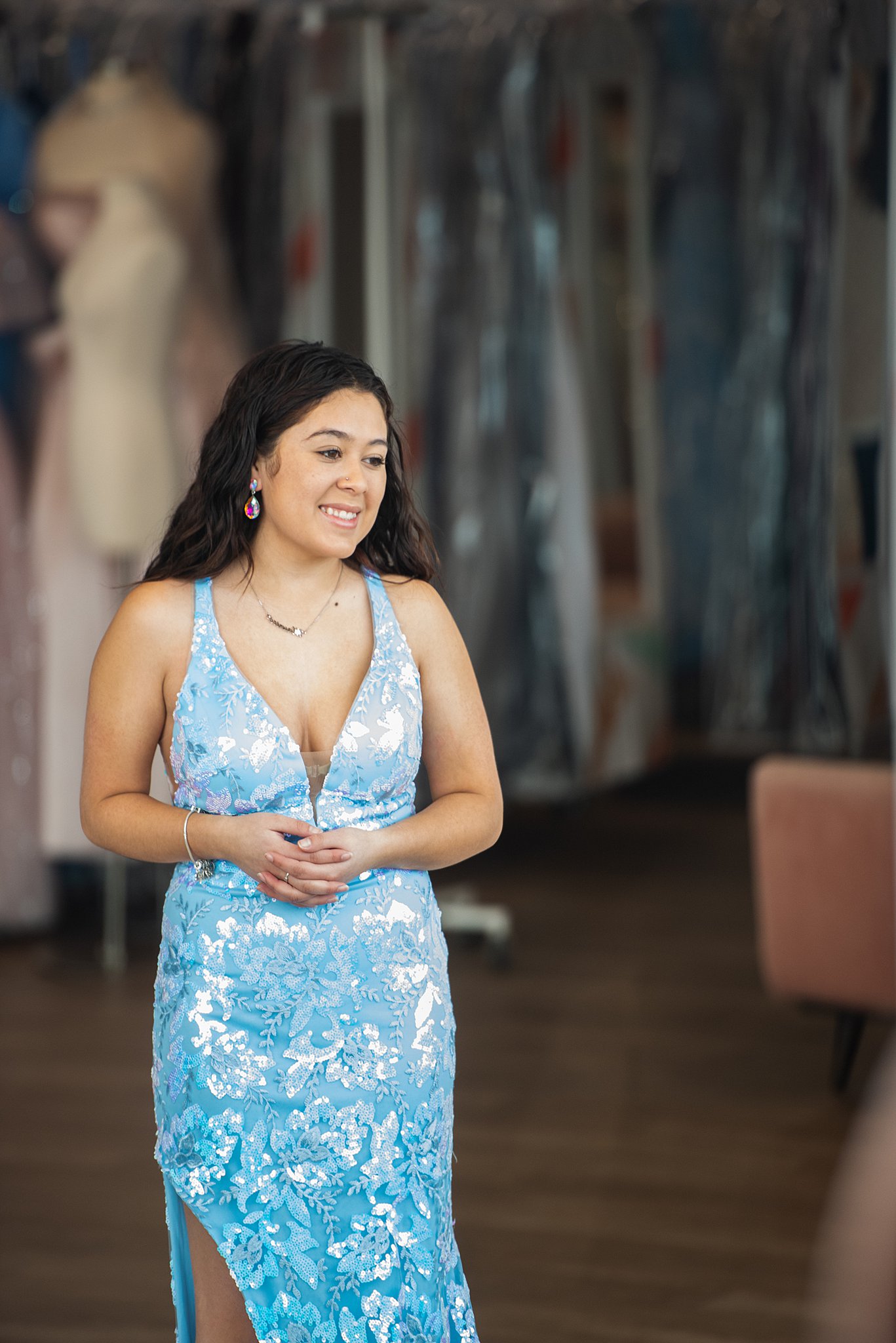 a woman wearing a blue floral gown stands in the store Something New Boutique