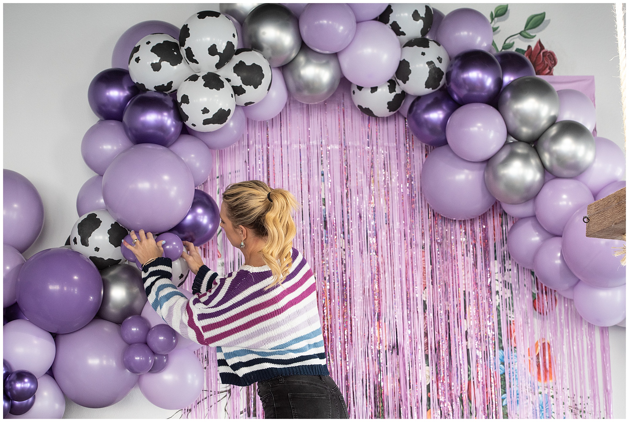 a woman works on finalizing balloon decorations for a birthday party