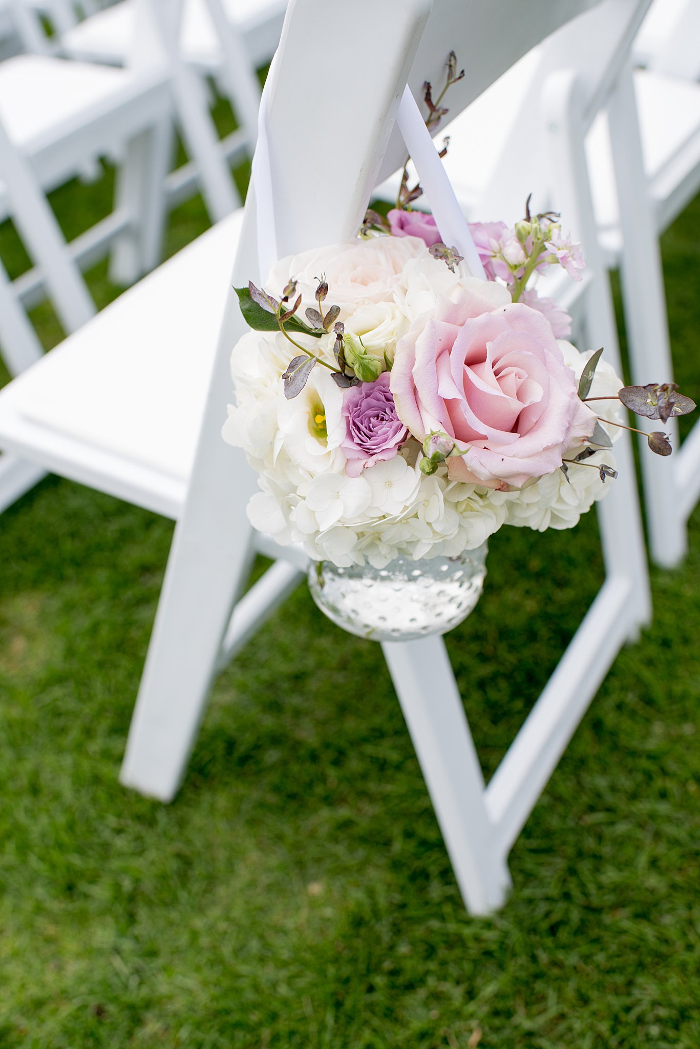 Details of a pink and white floral hanging on a chair at a wedding ceremony