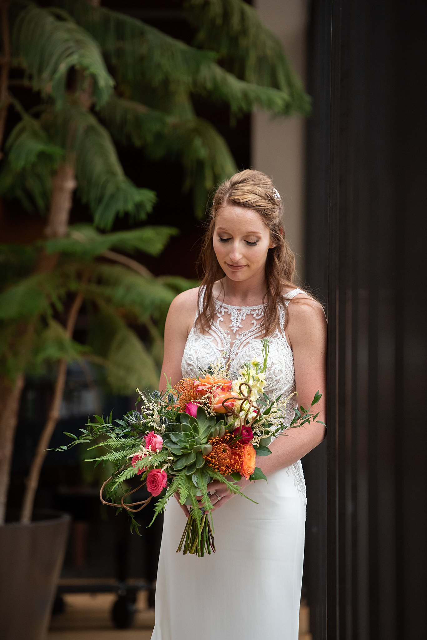 A bride smiles down out her colorful bouquet made by a castle rock florist
