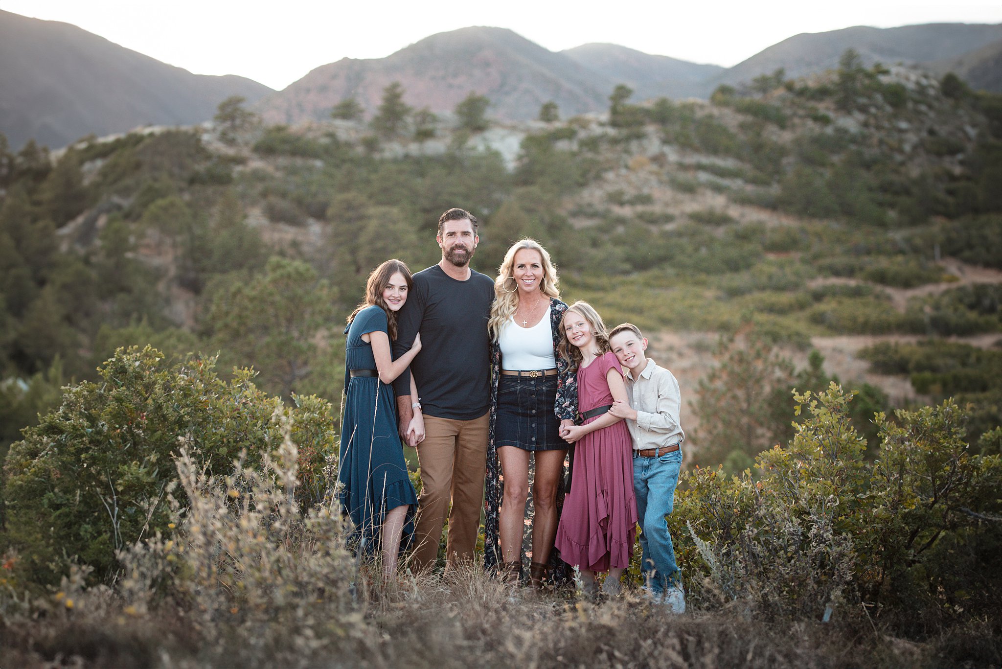 A mom and dad stand on a mountain trail as their three children lean on them thanks to castle rock pediatricians