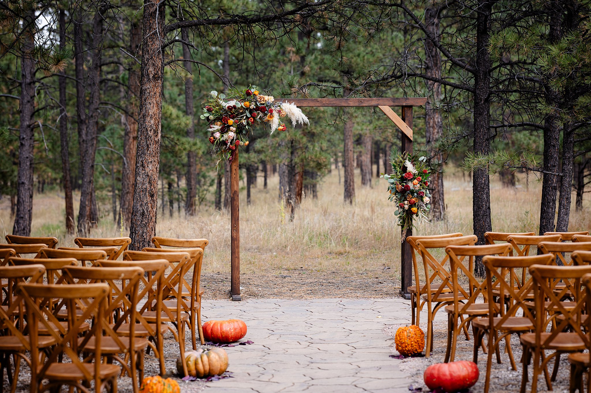 Details of a wooden arbor and chairs set for a fall wedding at one of the castle rock wedding venues