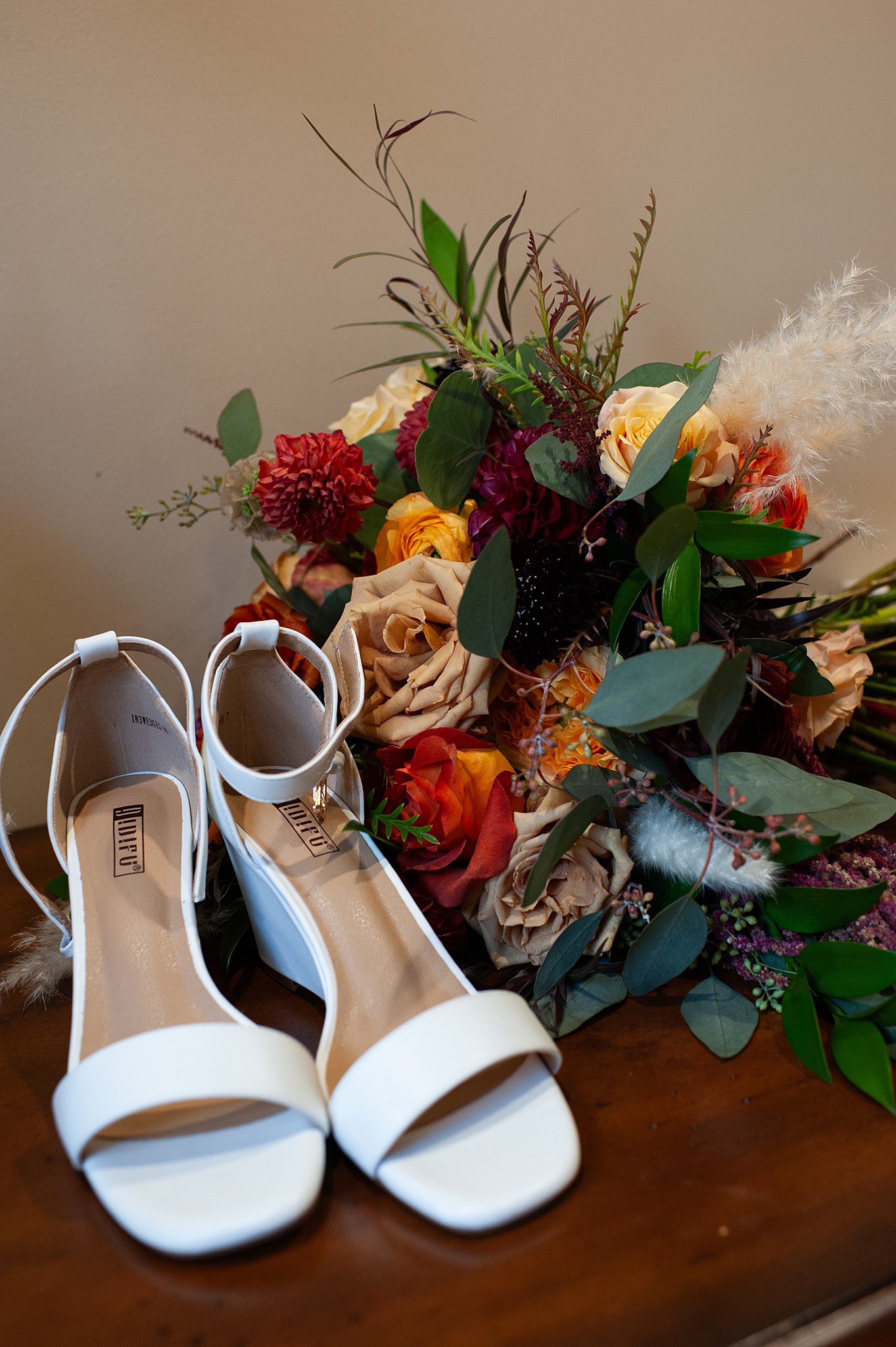 Details of shoes and a bouquet sitting on a wood table