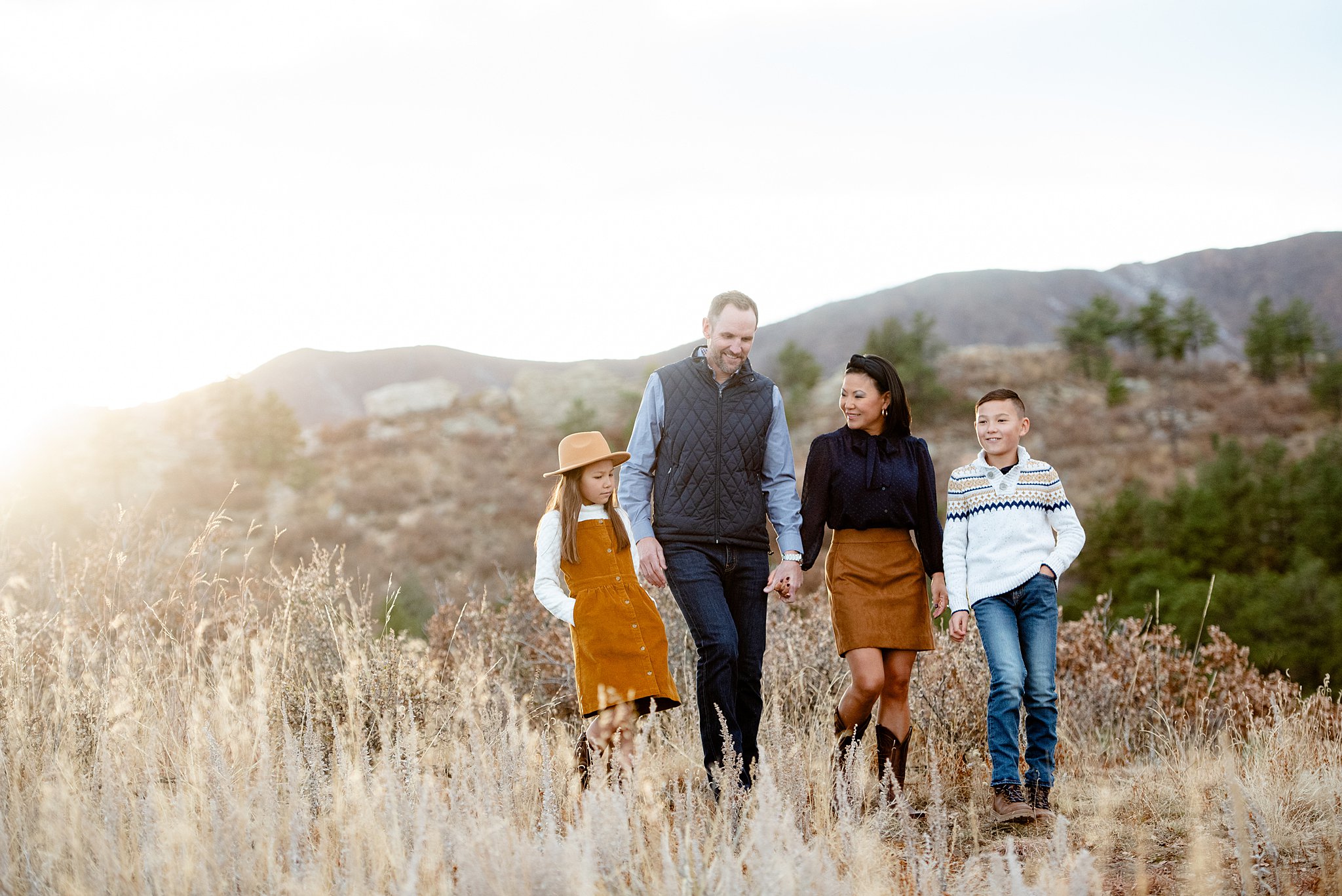 A mom and dad walk through a mountain trail with their young son and daughter after visiting a colorado springs pediatric dentistry