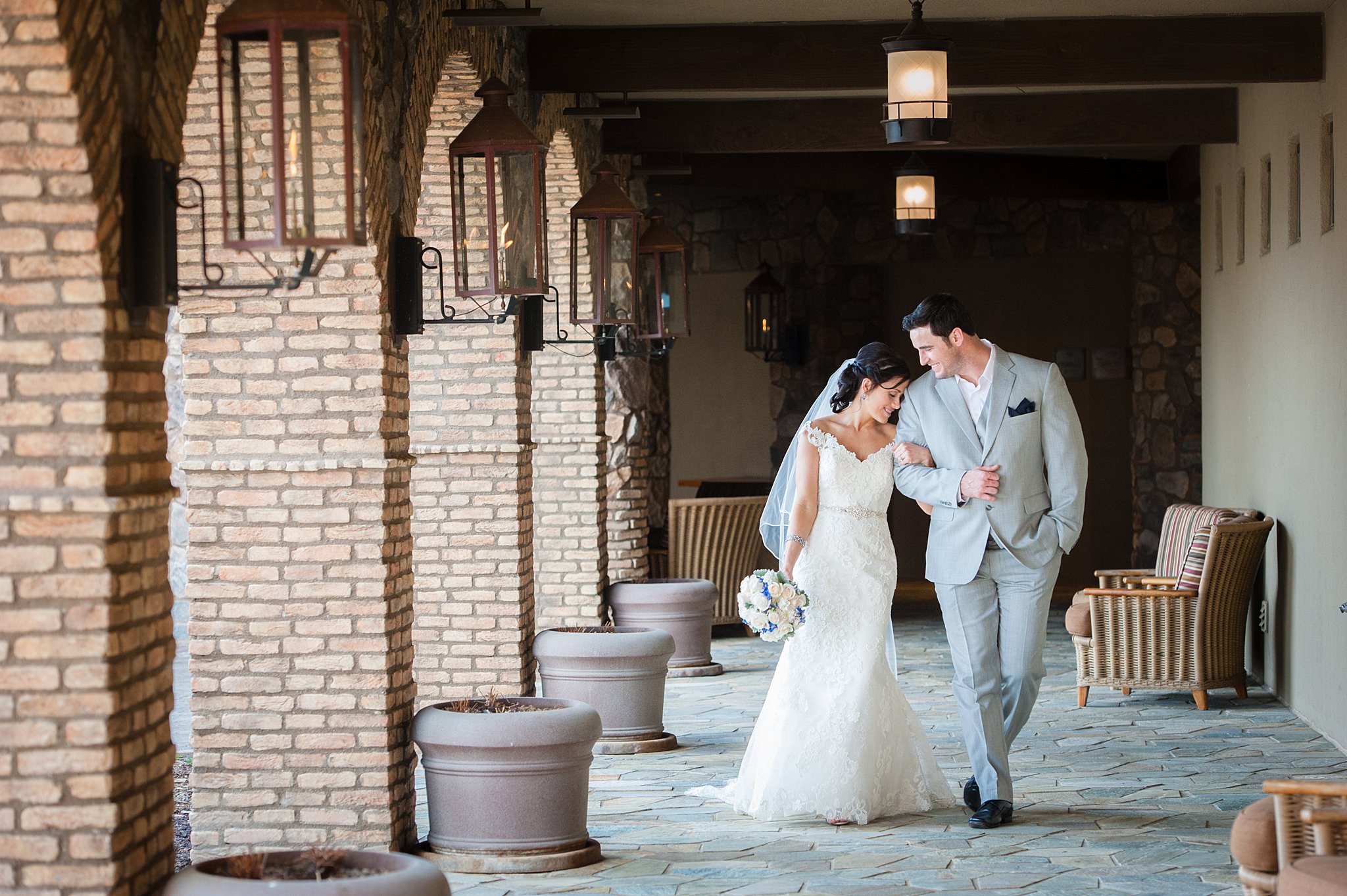 Newlyweds walk through a brick and stone porch arm in arm at one of the Colorado Springs Wedding Venues