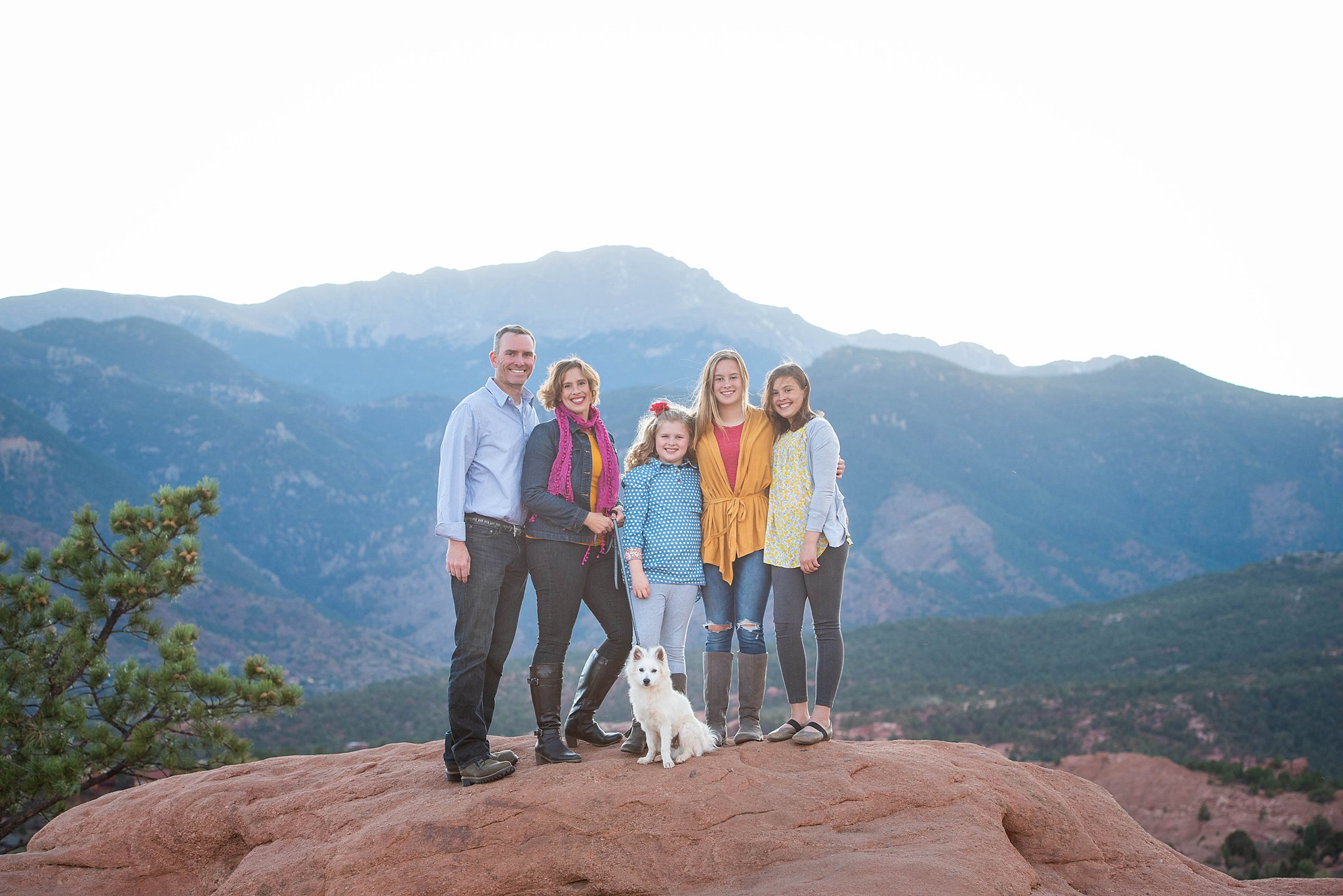 A family of 5 stand together on a mountain trail rock after visiting colorado springs yoga studios