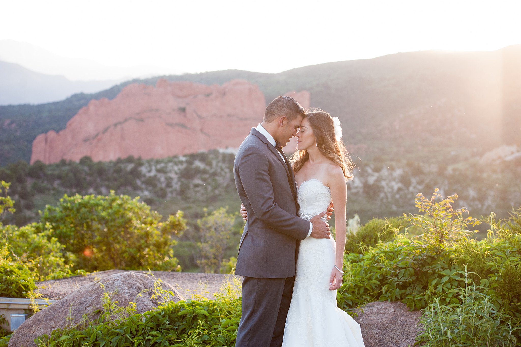 NEwlyweds share an intimate moment on a mountain trail at their Garden of The Gods Weddings at sunset