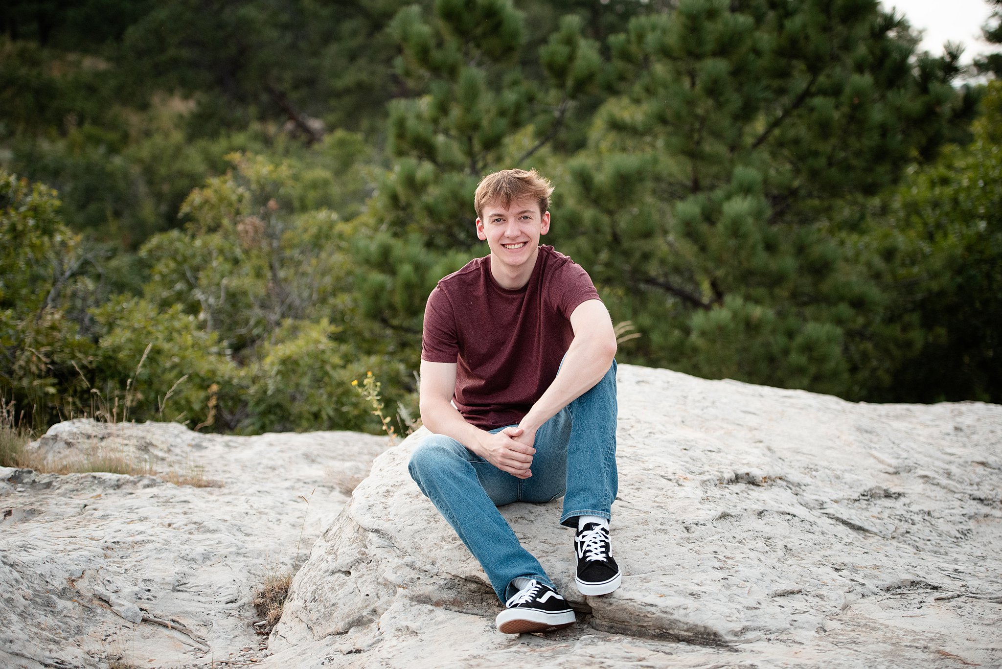 A high school senior sits on a rock on a mountain trail at ute valley park