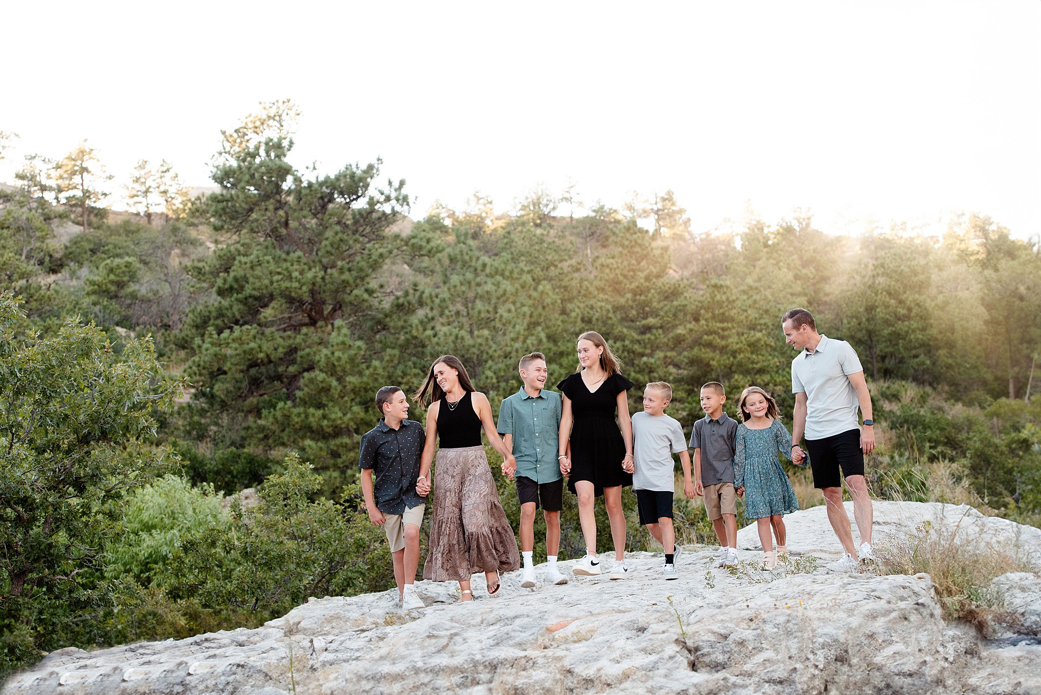 A family of eight walks through a rocky mountain trail holding hands at sunset at ute valley park
