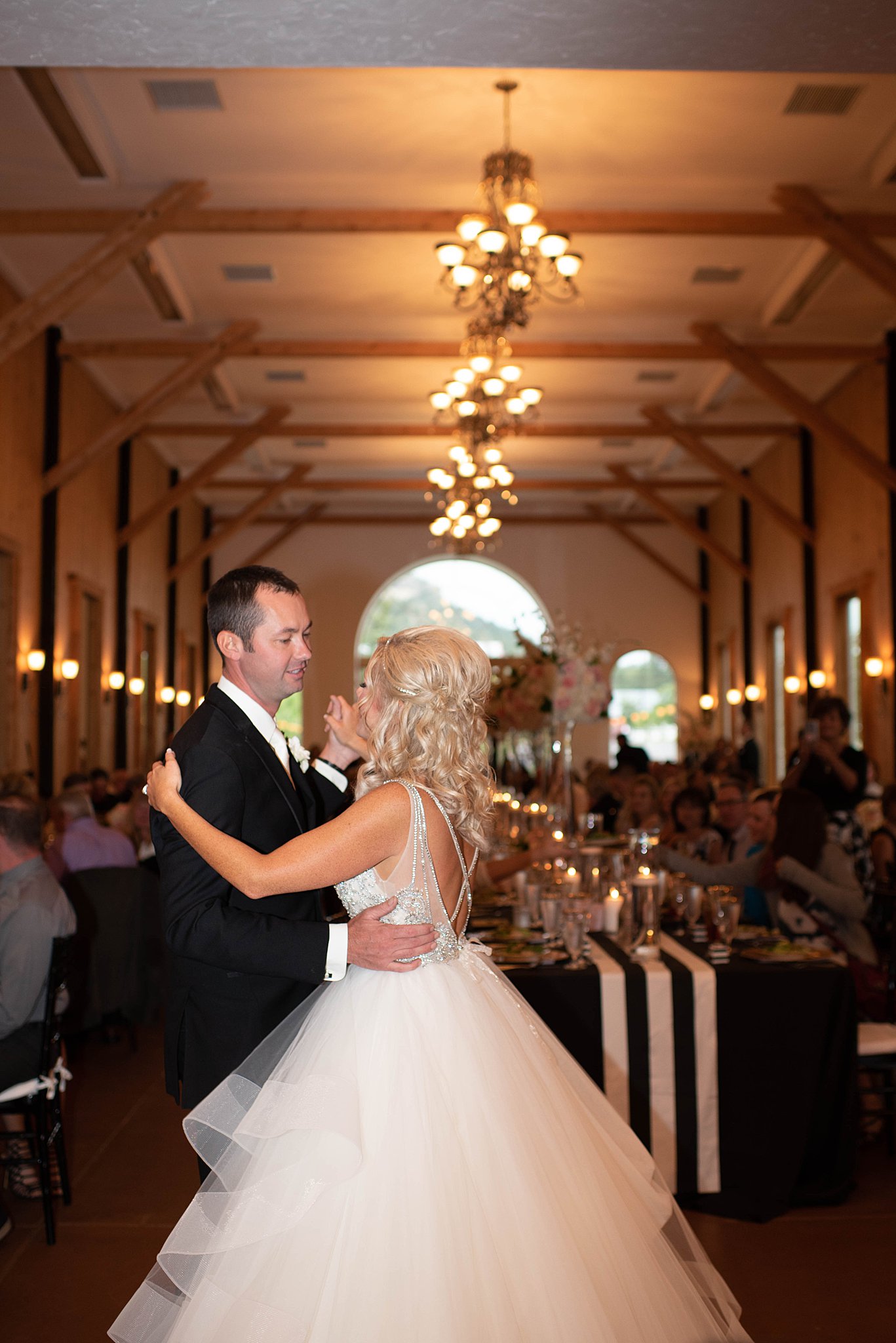 Newlyweds dance in a lang reception room in front of guests