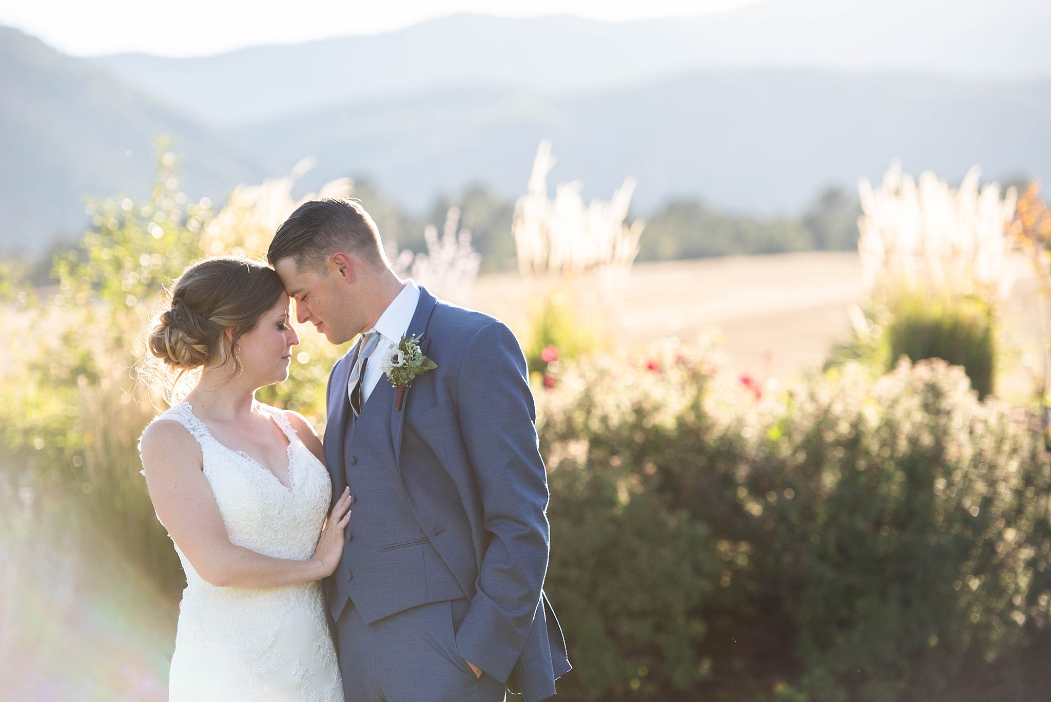 Newlyweds touch foreheads sharing an intimate moment in a garden at a Wine and Nosh wedding