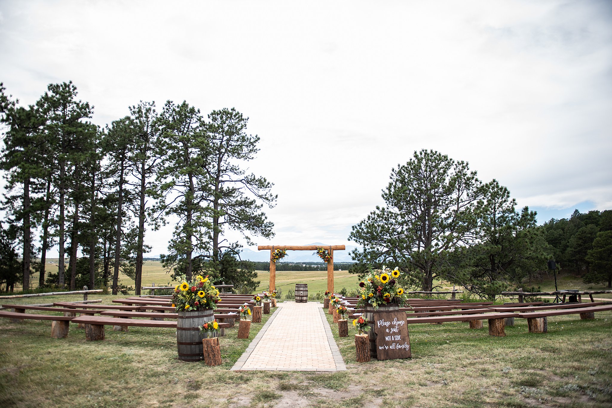 Details of a wedding ceremony set up outside in a pasture with log arbor and benches