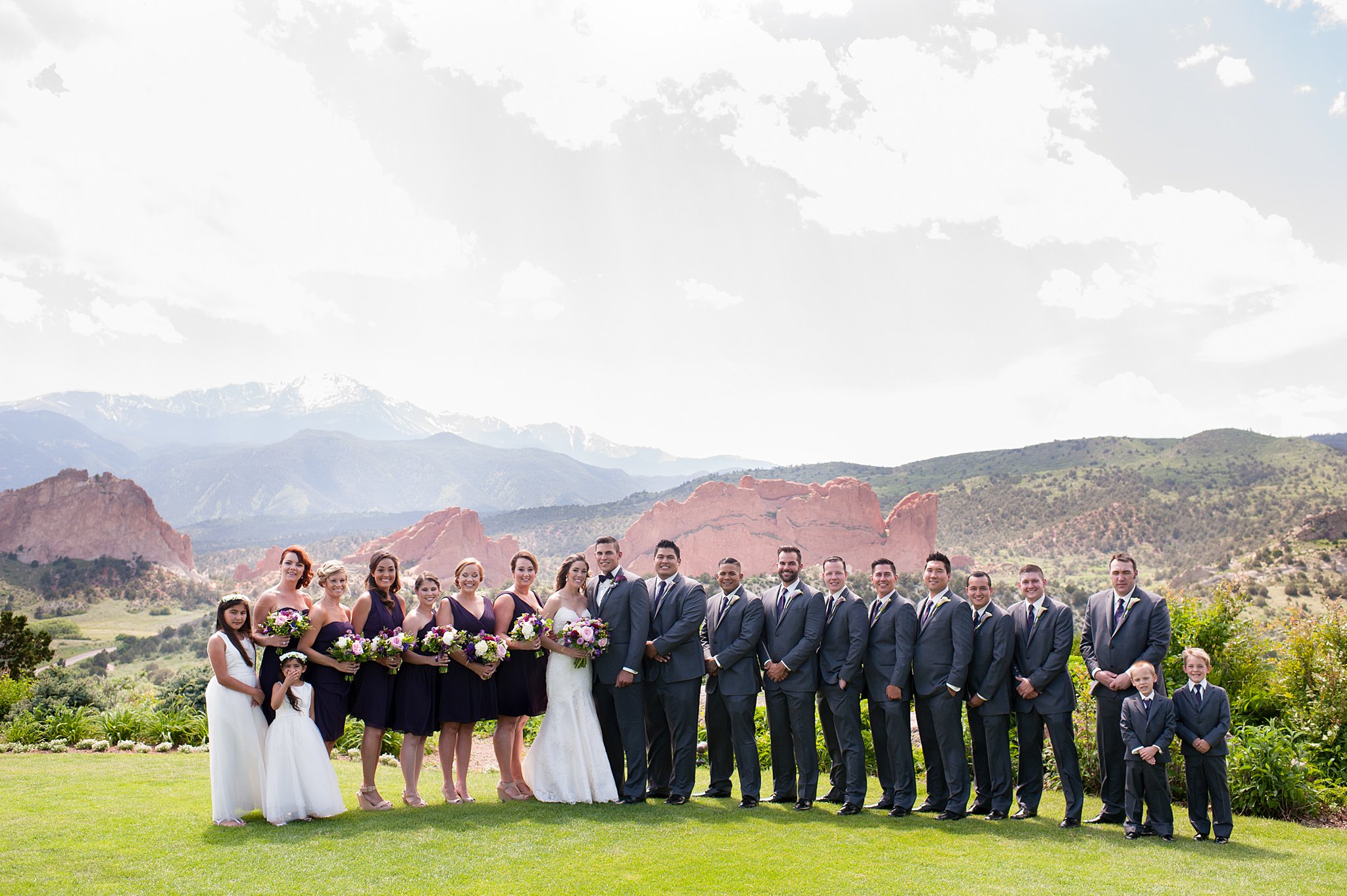 Newlyweds stand with their large wedding party on the lawn at their Garden Of The Gods Club Wedding