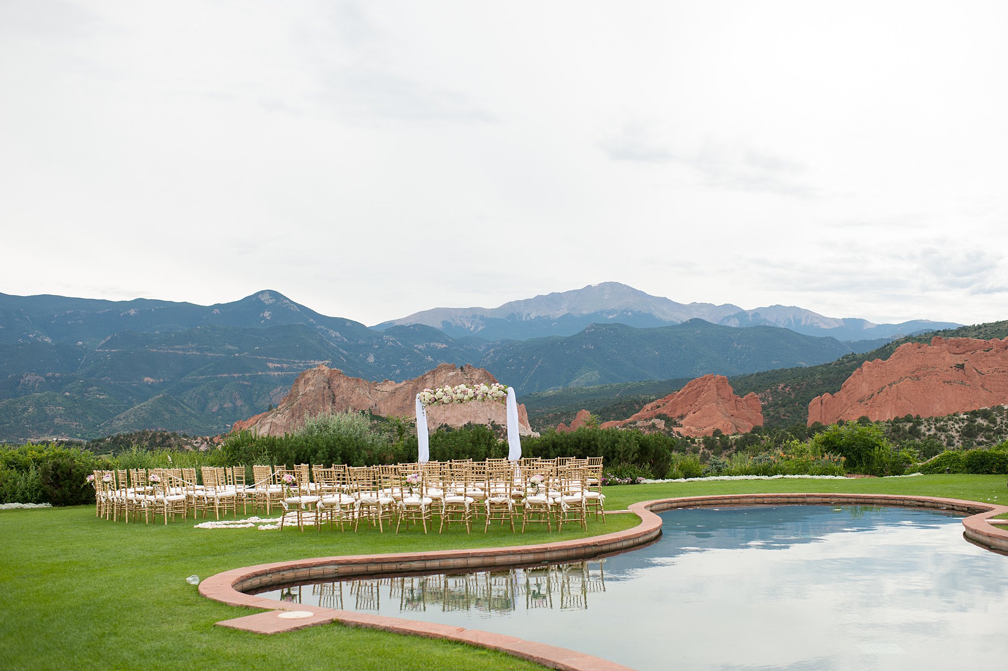 A view of the epic outdoor wedding ceremony location with golden chairs