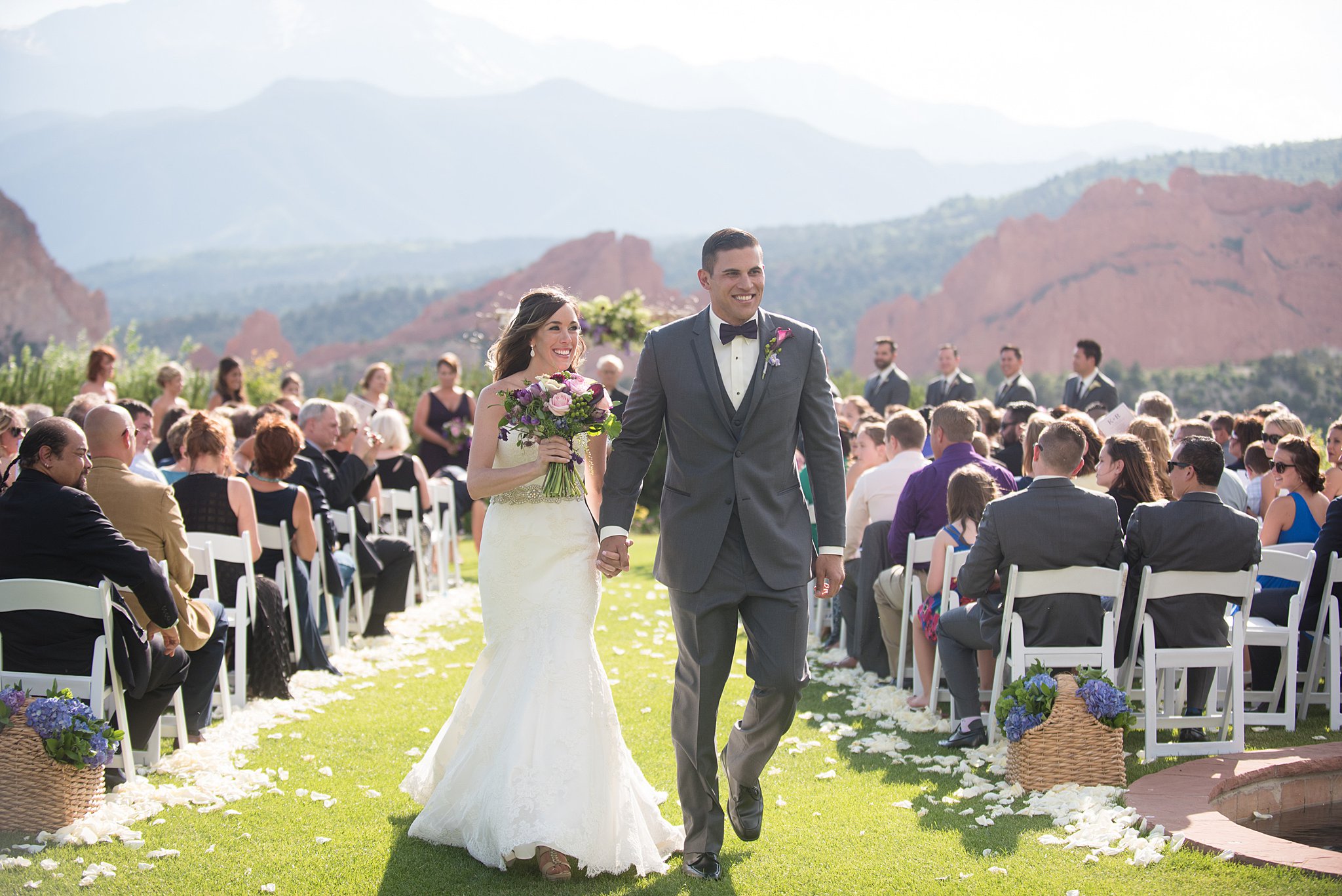 Newlyweds hold hands while exiting their outdoor Garden Of The Gods Club Wedding ceremony