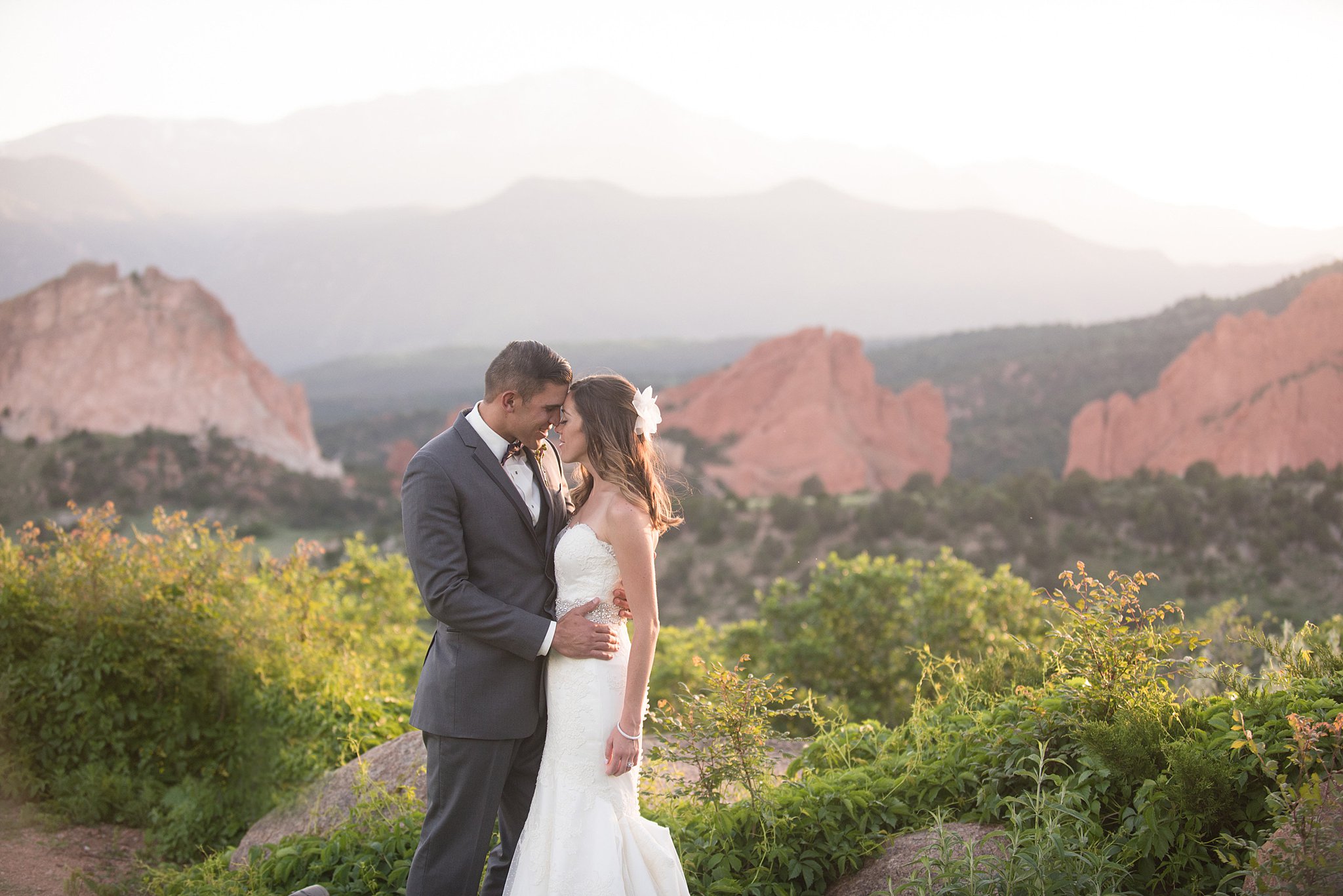 Newlyweds touch foreheads while cuddling at their Garden Of The Gods Club Wedding at sunset