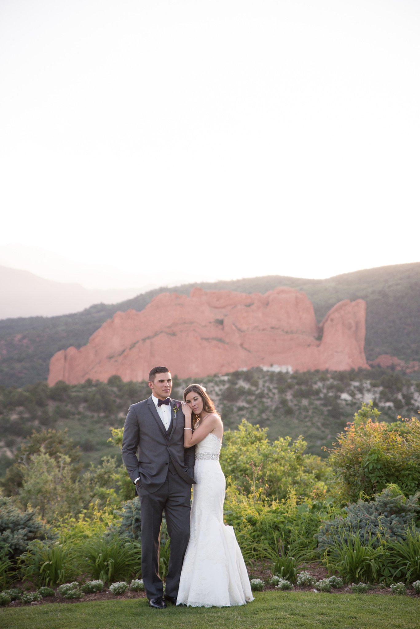 Newlyweds snuggle on the edge of a garden at the epic Garden Of The Gods Club Wedding