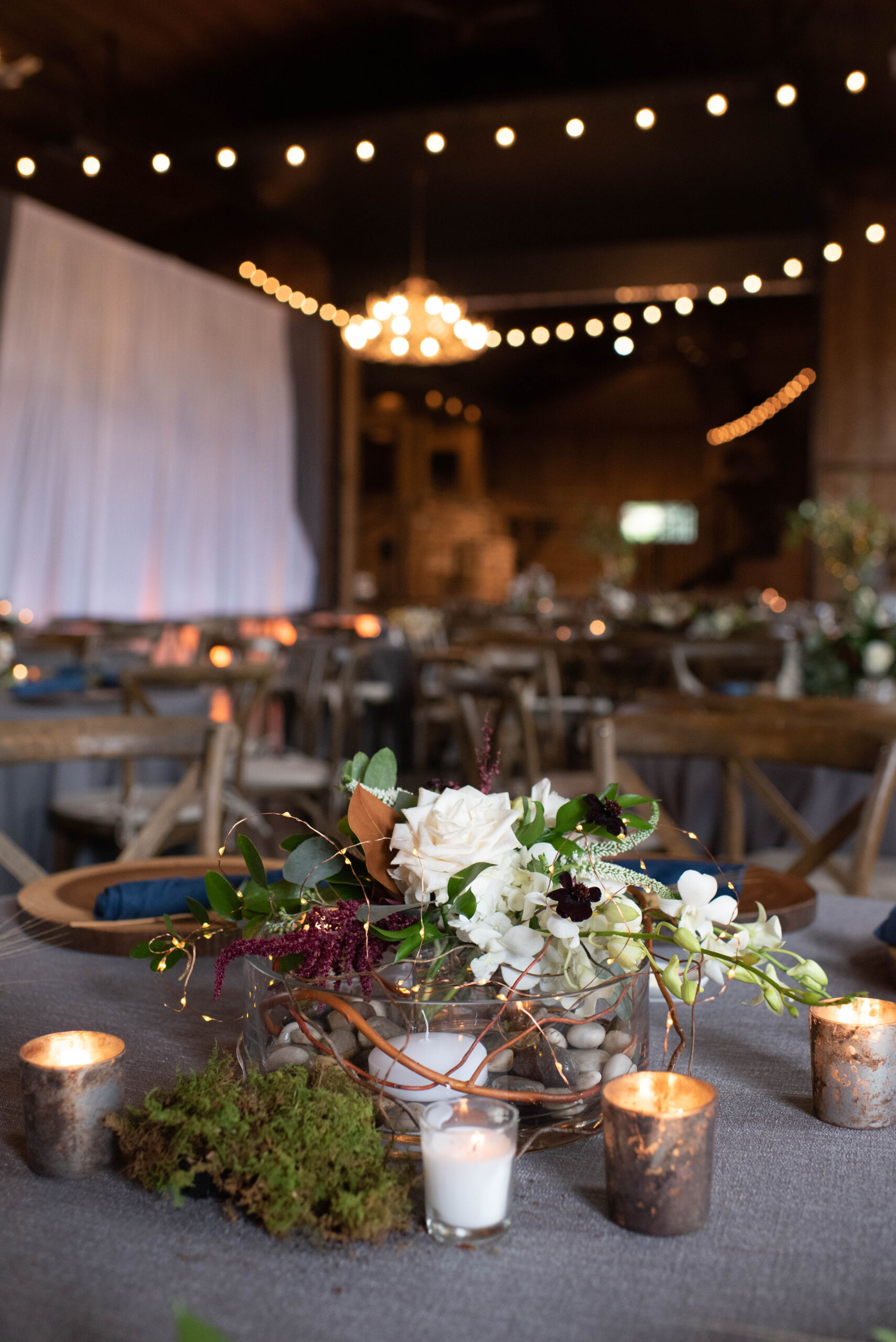 Details of a Spruce Mountain Ranch wedding reception centerpiece with candles and white roses in a rock vase