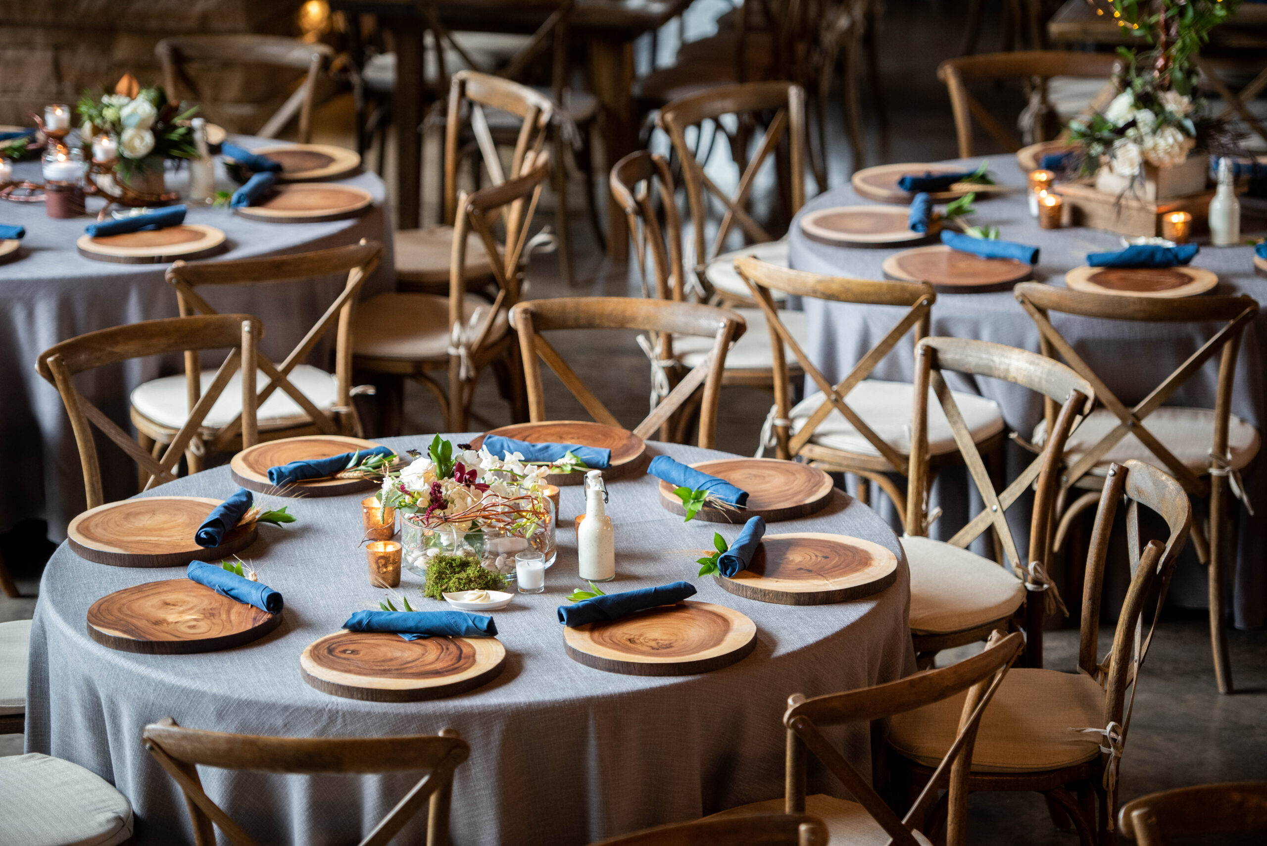 Details of a Spruce Mountain Ranch wedding reception with wooden chargers and blue napkins and wooden chairs