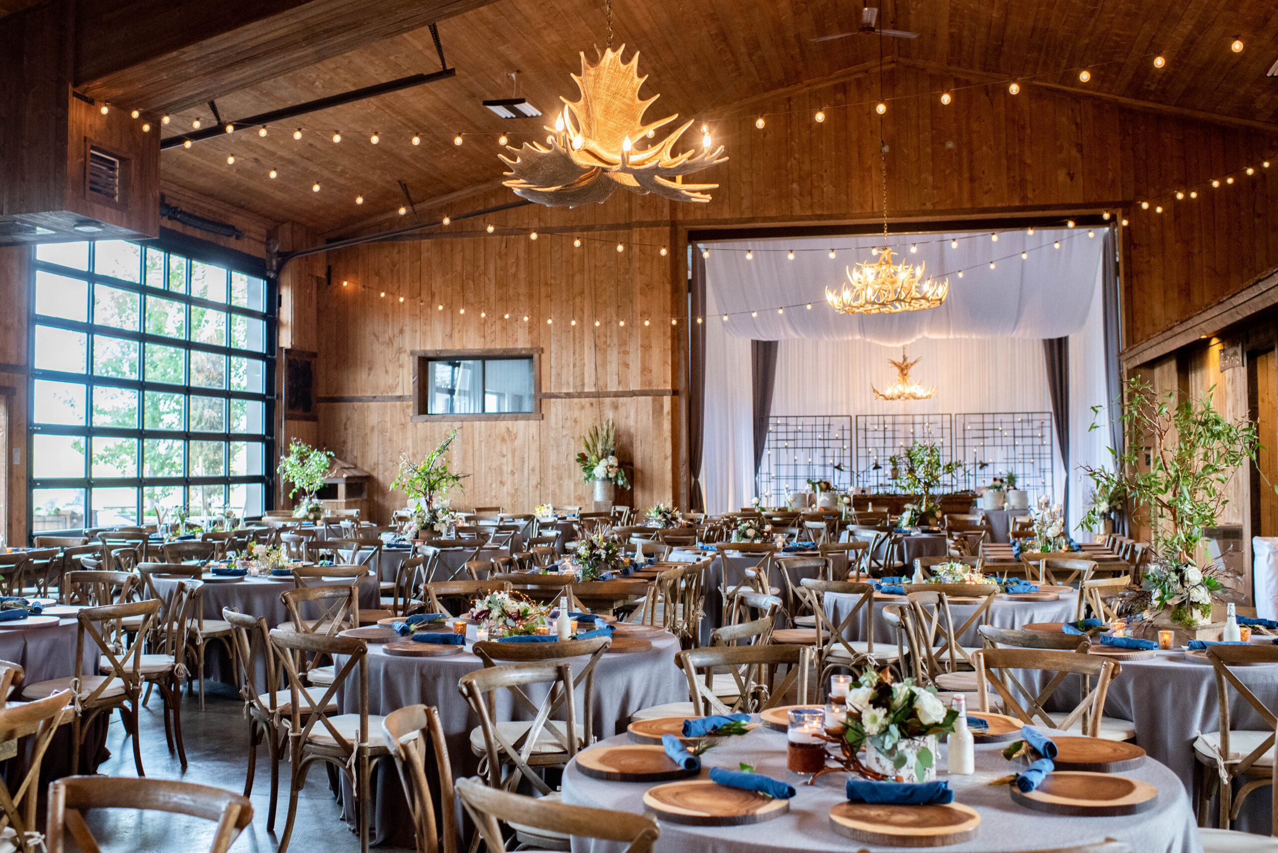 A Spruce Mountain Ranch wedding reception set up with grey linens and antler chandeliers