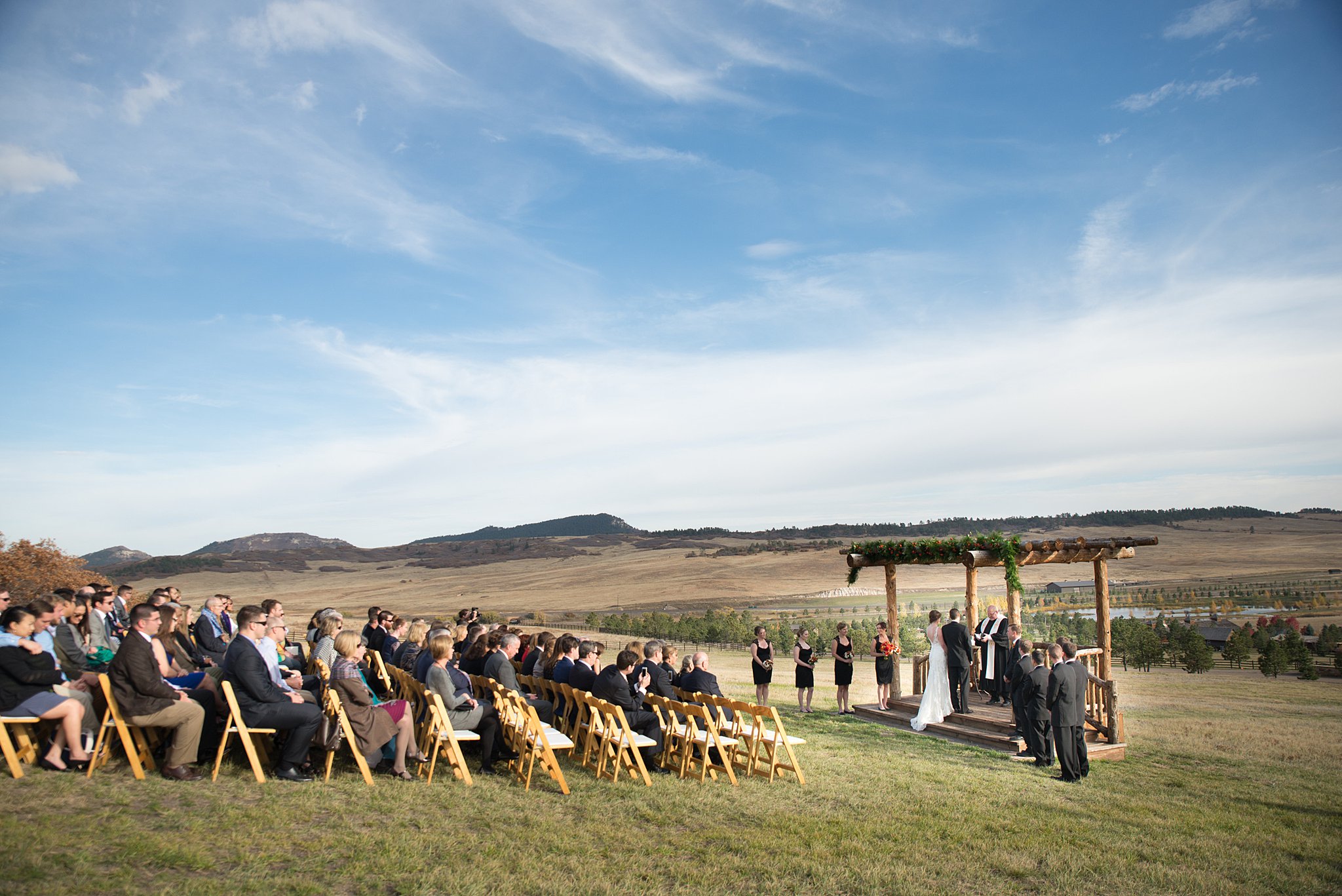 A view of a Spruce Mountain Ranch wedding ceremony on the deck with wooden chairs