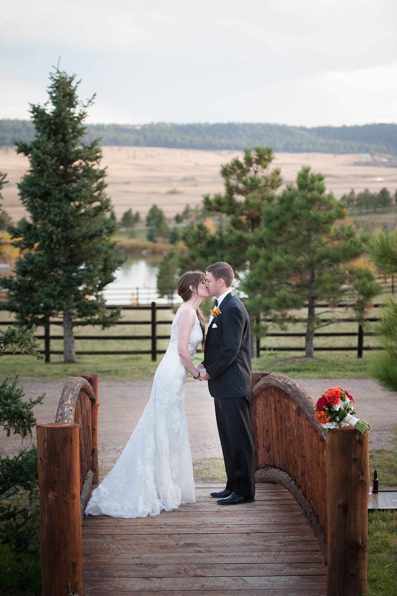 Newlyweds kiss on a wooden bridge at their Spruce Mountain Ranch wedding