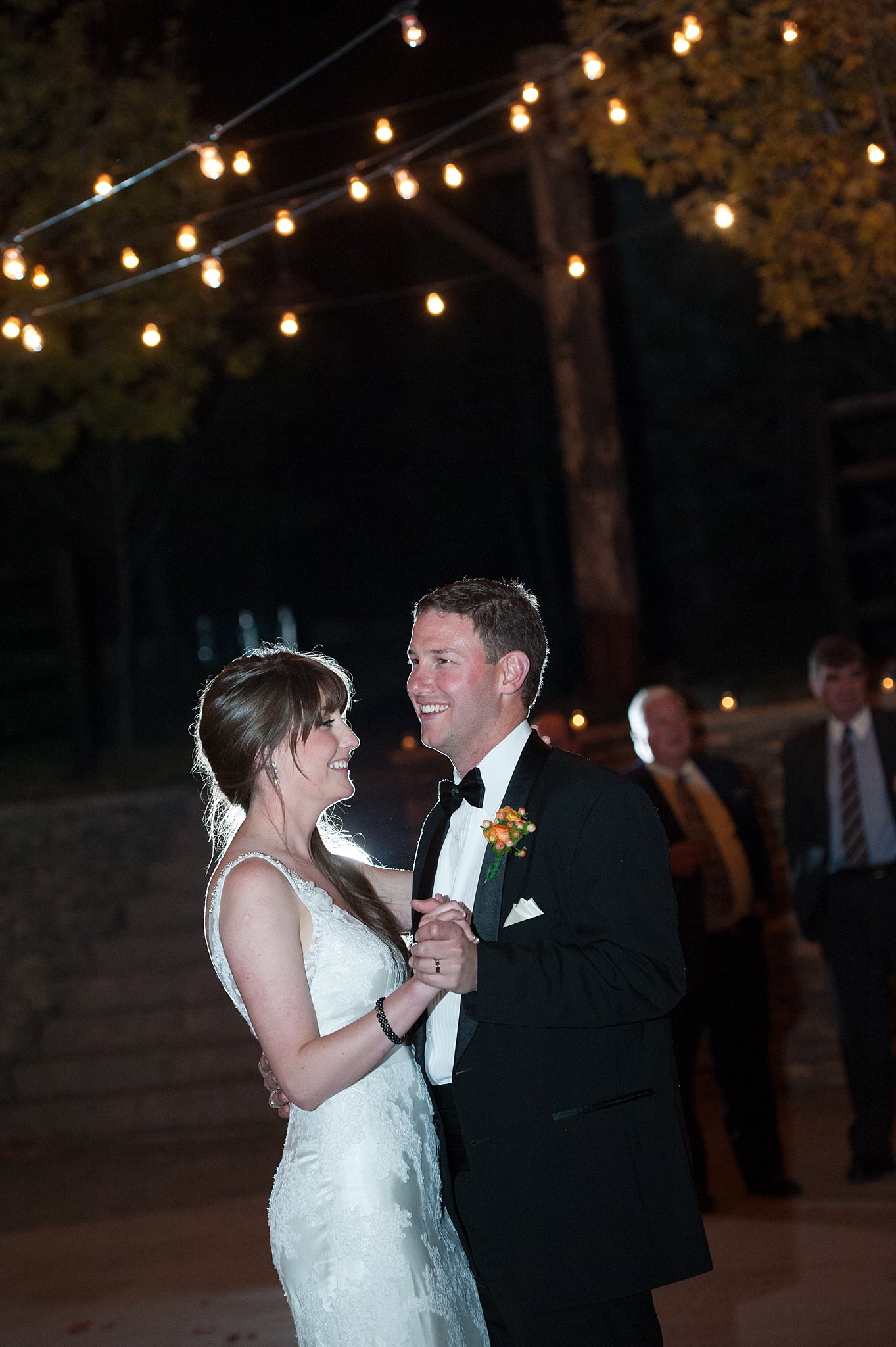 A bride and groom smile big while dancing under market lights at their Spruce Mountain Ranch wedding