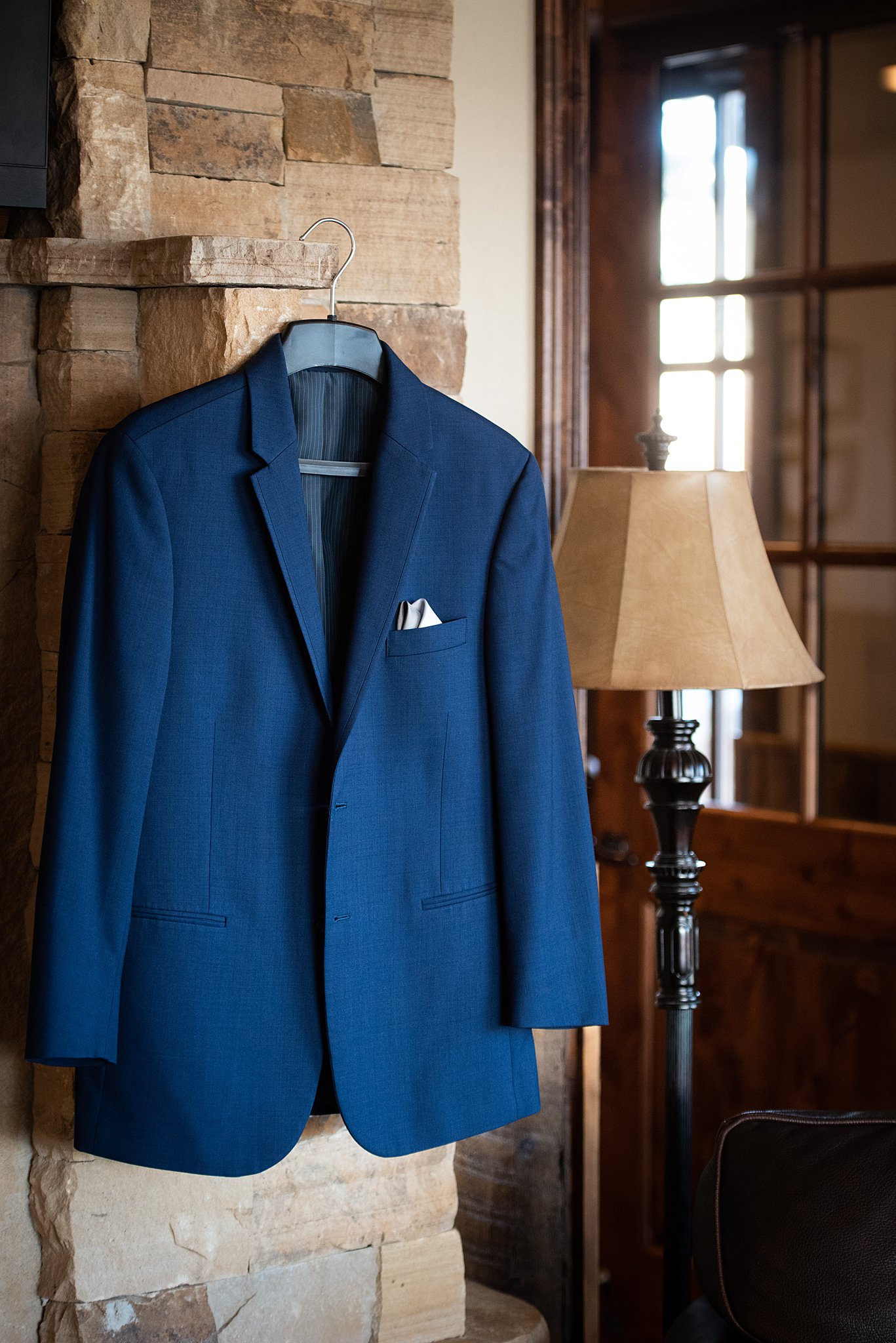 A blue suit jacket hangs on a stone fireplace wall