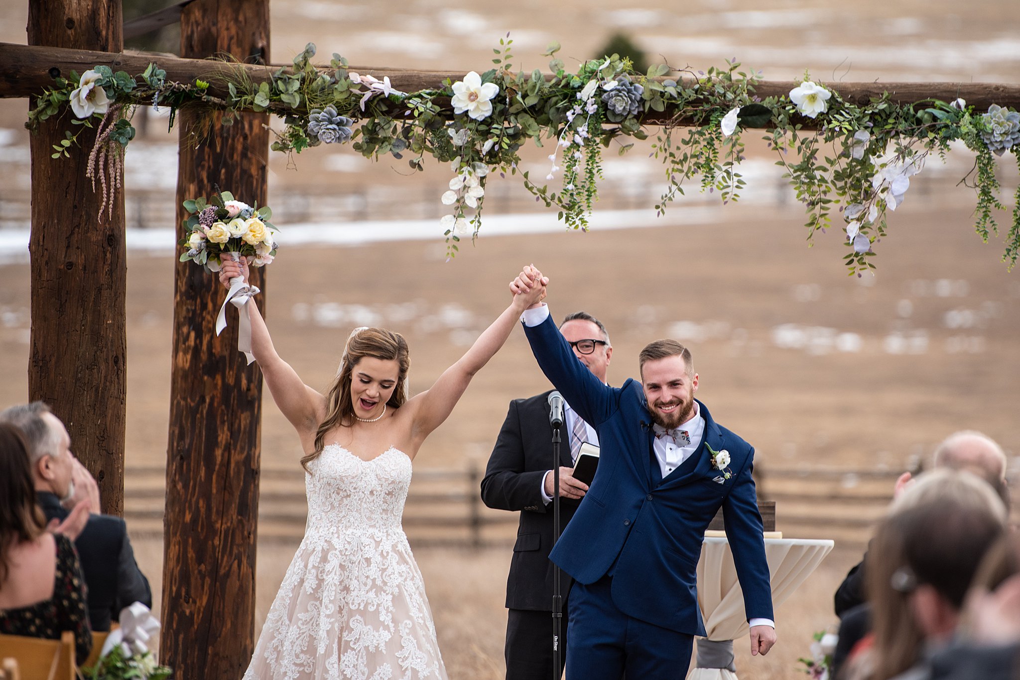 Newlyweds celebrate at the altar to end their Spruce Mountain Ranch wedding ceremony with hands up