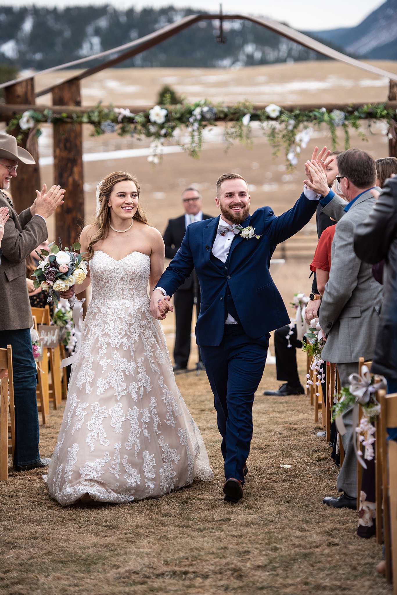 Newlyweds walk up the aisle giving high fives after their ceremony at their outdoor Spruce Mountain Ranch wedding