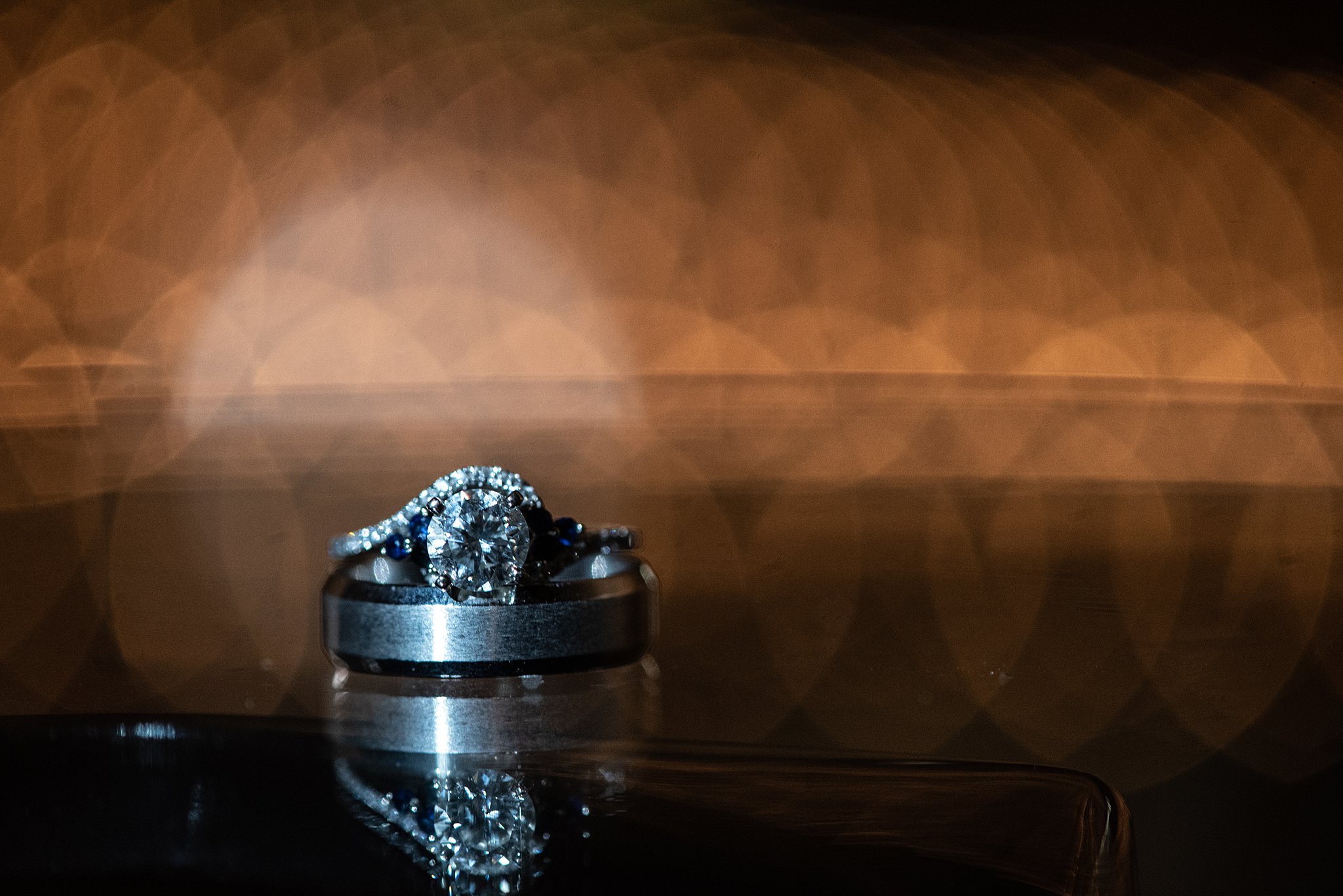 Details of an engagement ring sitting on a groom's wedding band