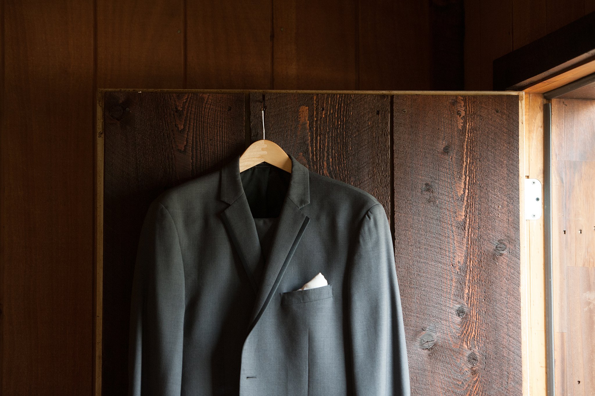 Details of a dark suit handing from a wooden door in a cabin