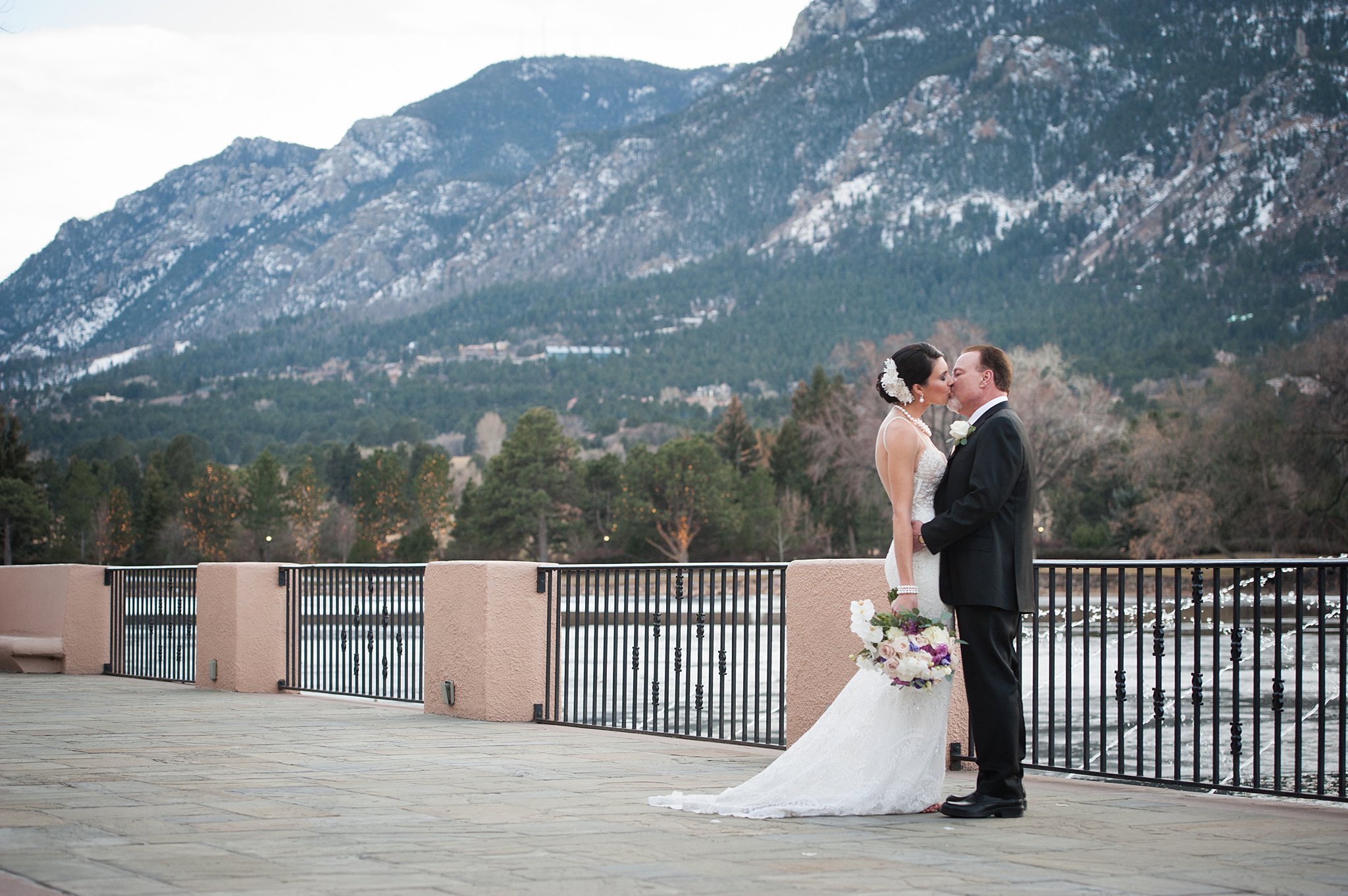 Newlyweds kiss by the water with fountains on at The Broadmoor Wedding venue