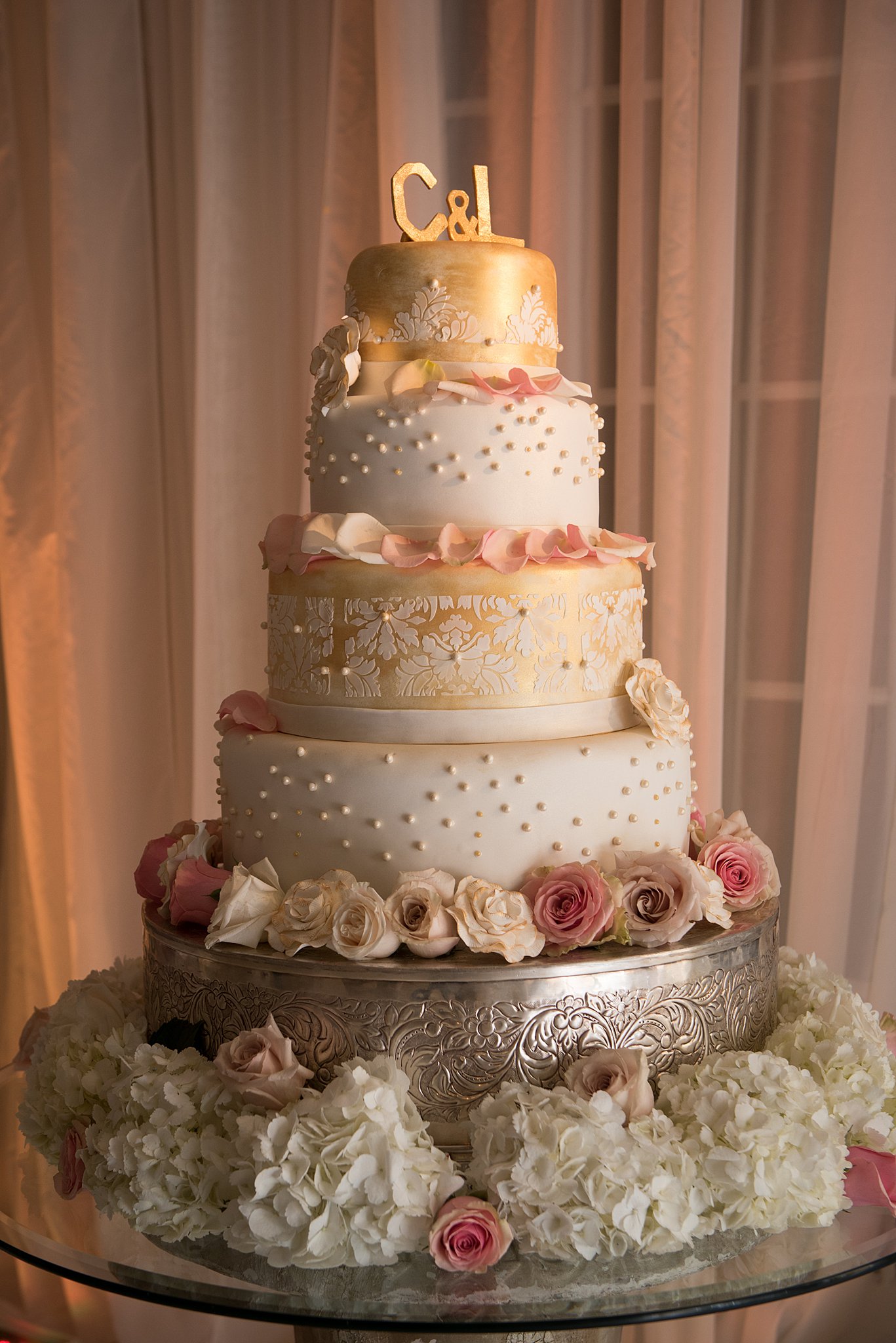 An ornate three tier wedding cake with flowers sits on a table at The Broadmoor Wedding venue