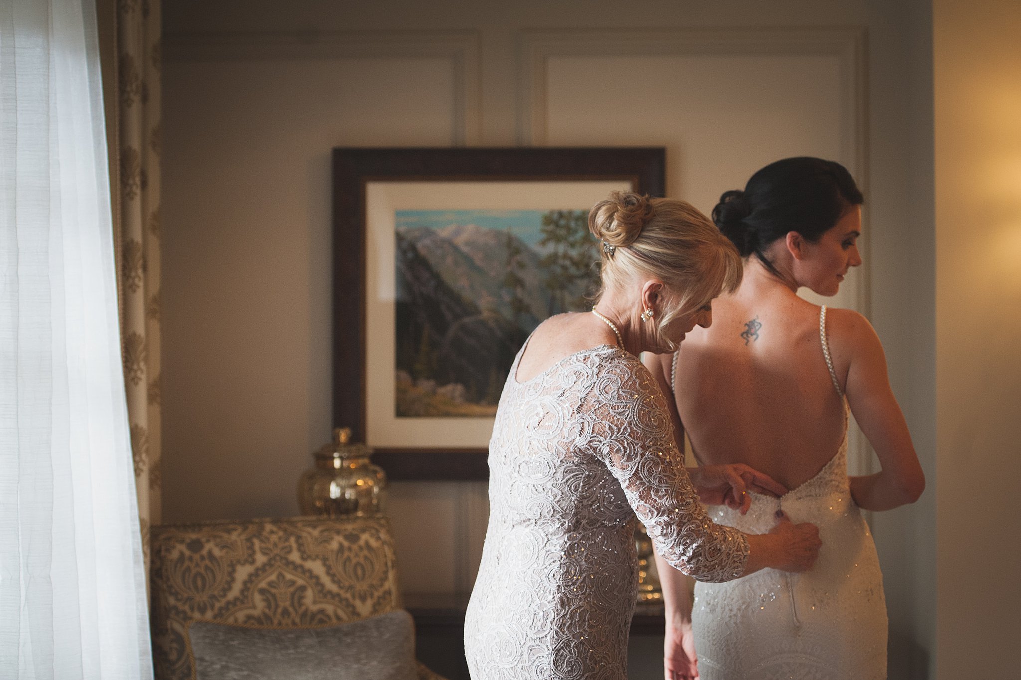 Mom helps the bride zip up her dress in the getting ready room