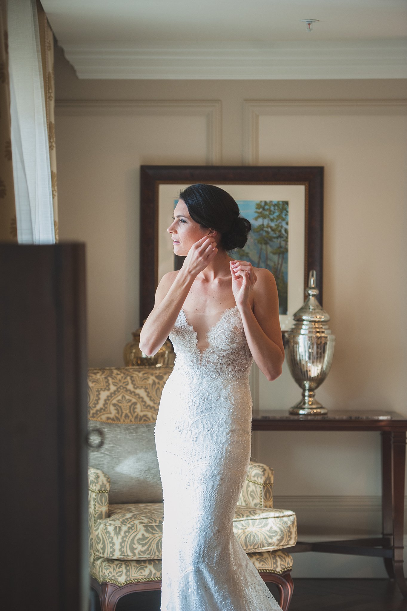 A bride puts in her earrings while getting ready in a window at The Broadmoor Wedding