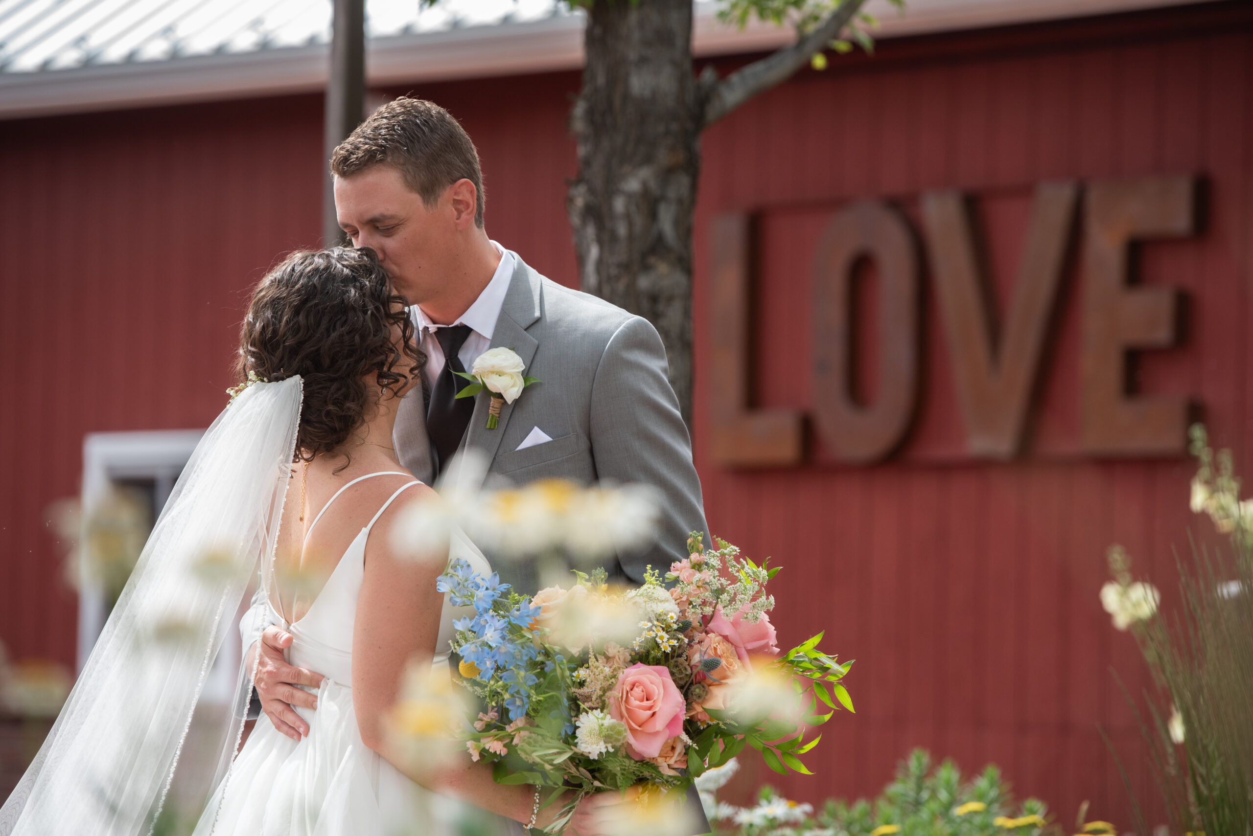 Newlyweds snuggle and kiss in the garden at their The Venue At Crooked Willow Farms Wedding